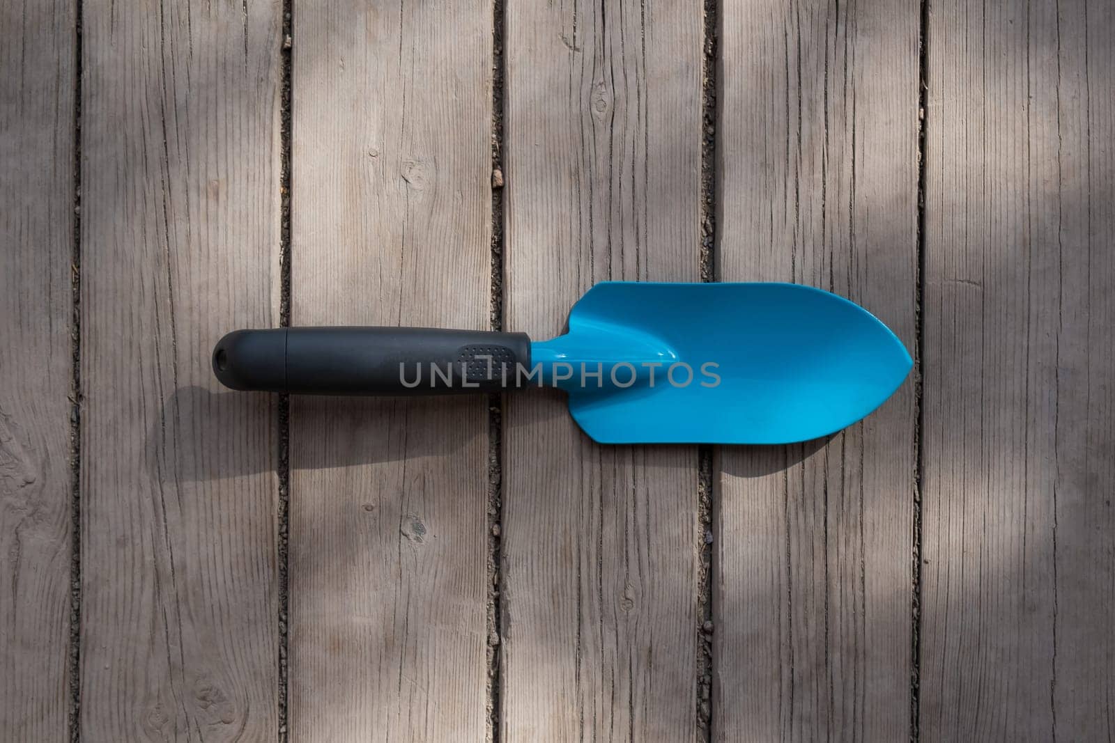 Small blue gardener's spatula on the wooden floor.