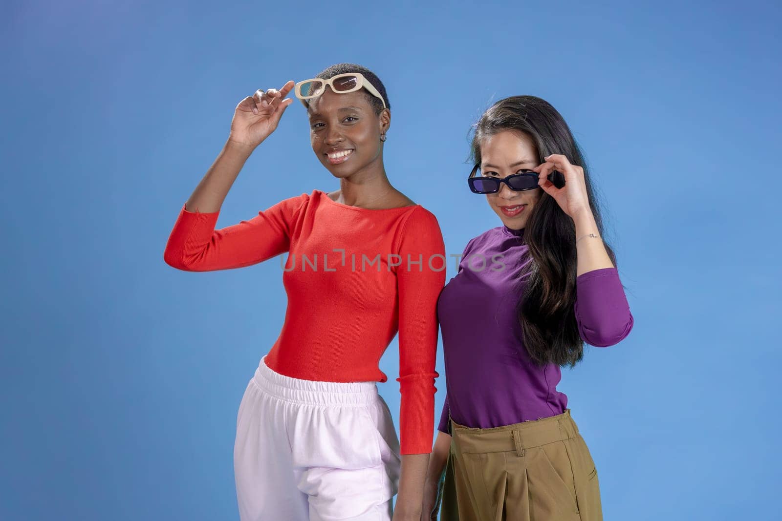 Young afro american and chinese woman with sunglasses over isolated background . High quality photo