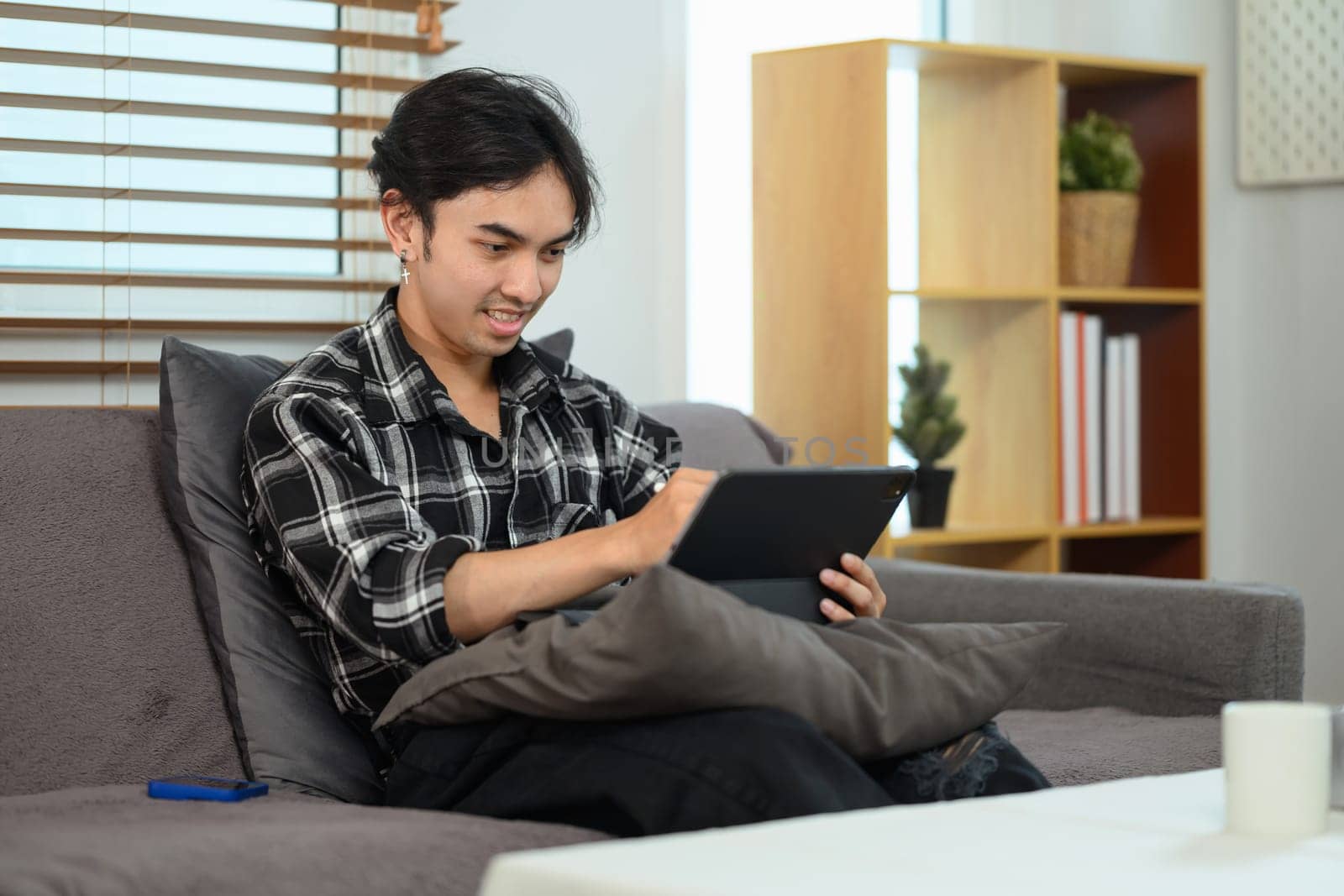 Handsome asian man shopping online, browsing Internet on digital tablet at home.