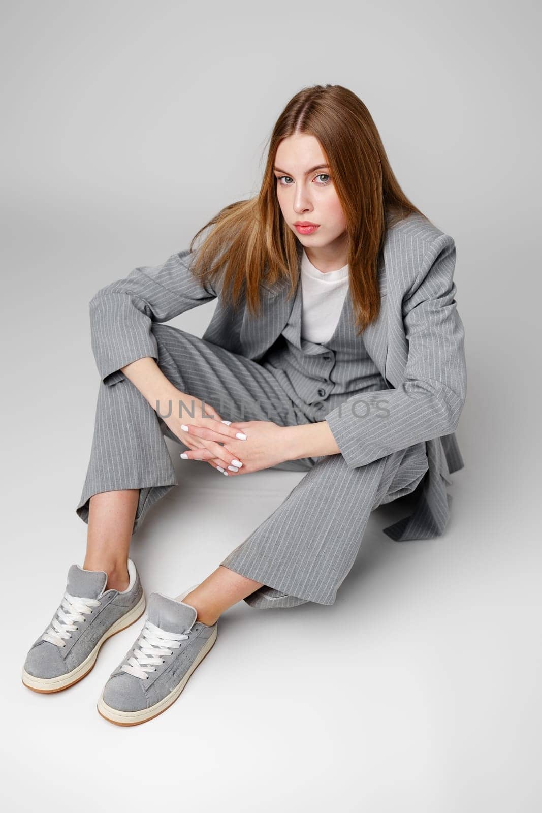 Young Woman in a Gray Suit Sitting on the Floor in Studio portrait