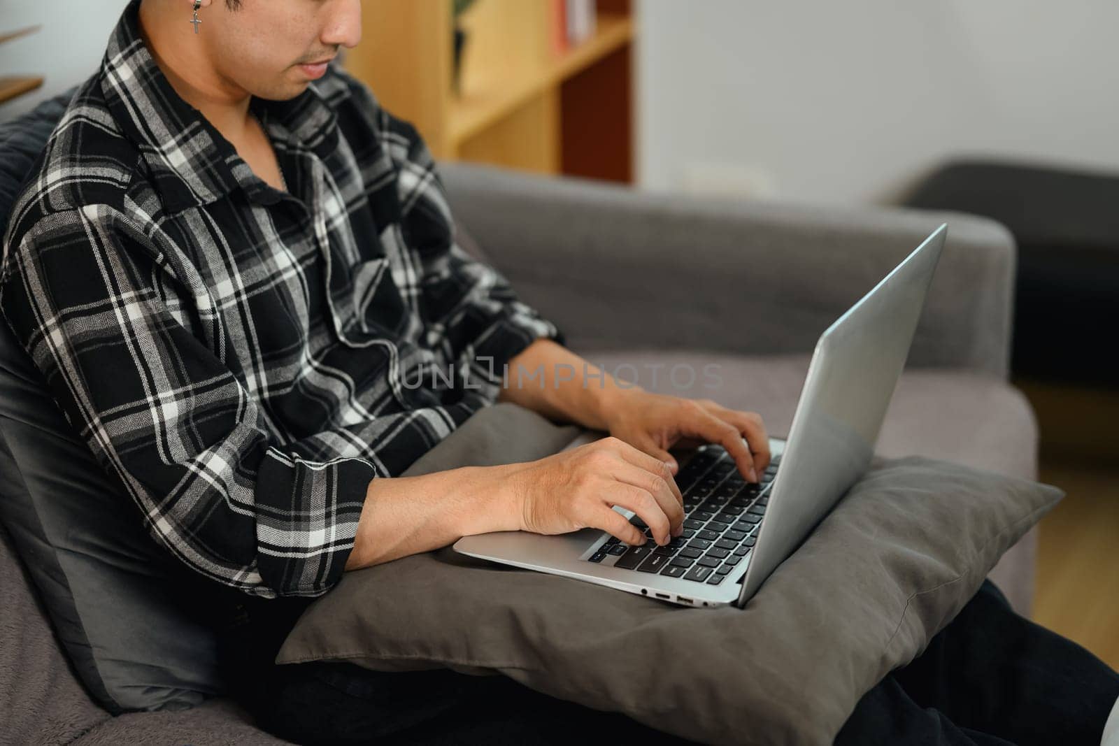 Young man sitting on couch and using laptop working remotely from home.