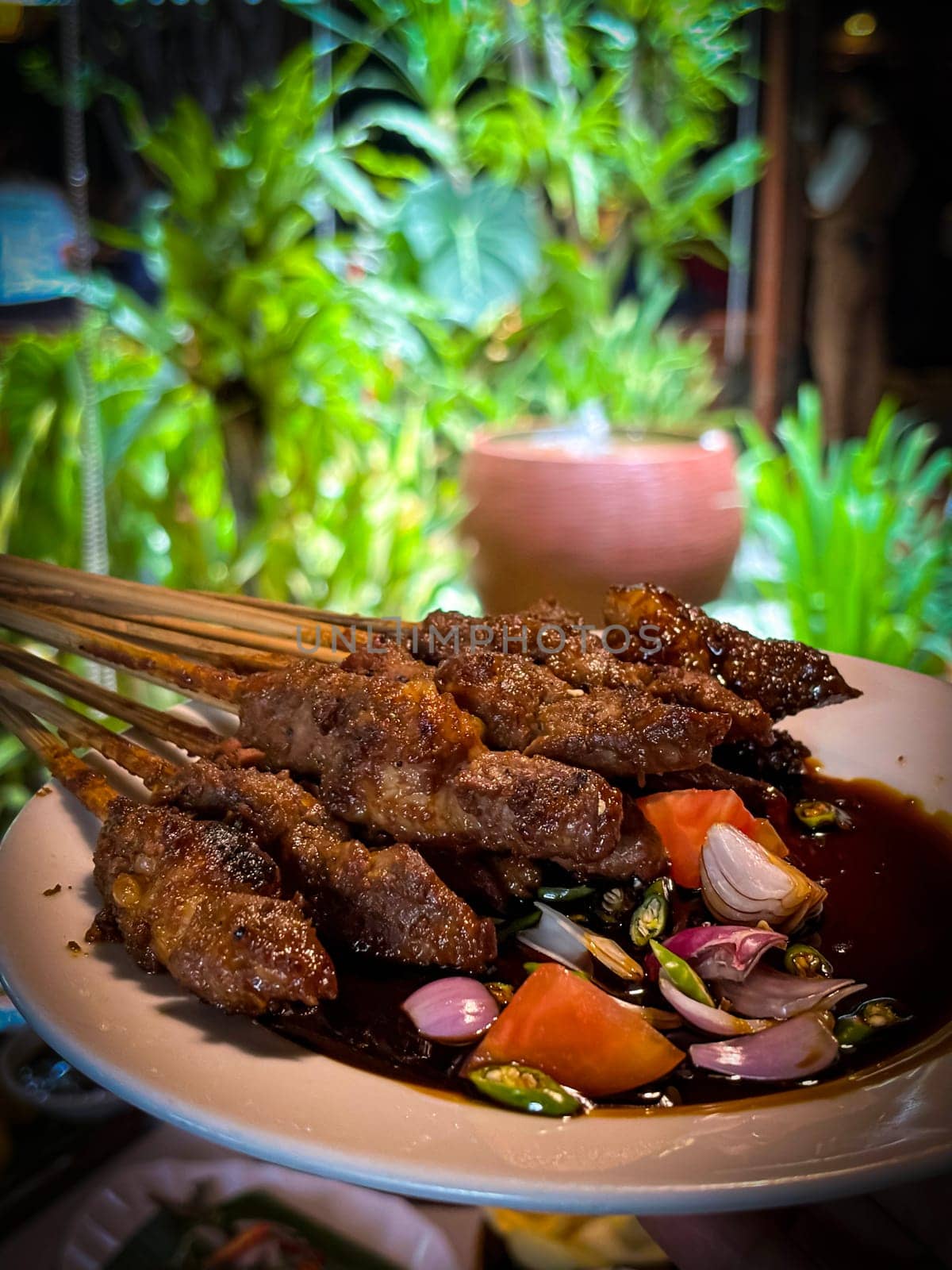 Lamb, mutton grilled skewer satay served with soy sauce sauce with sliced shallots, tomatoes, cucumber and cayenne pepper served in white plate by antoksena