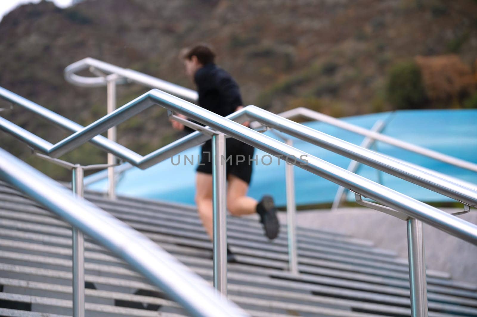 Unfocused athlete, running down the stairs, doing dynamic exercise outdoors by mariaphoto3