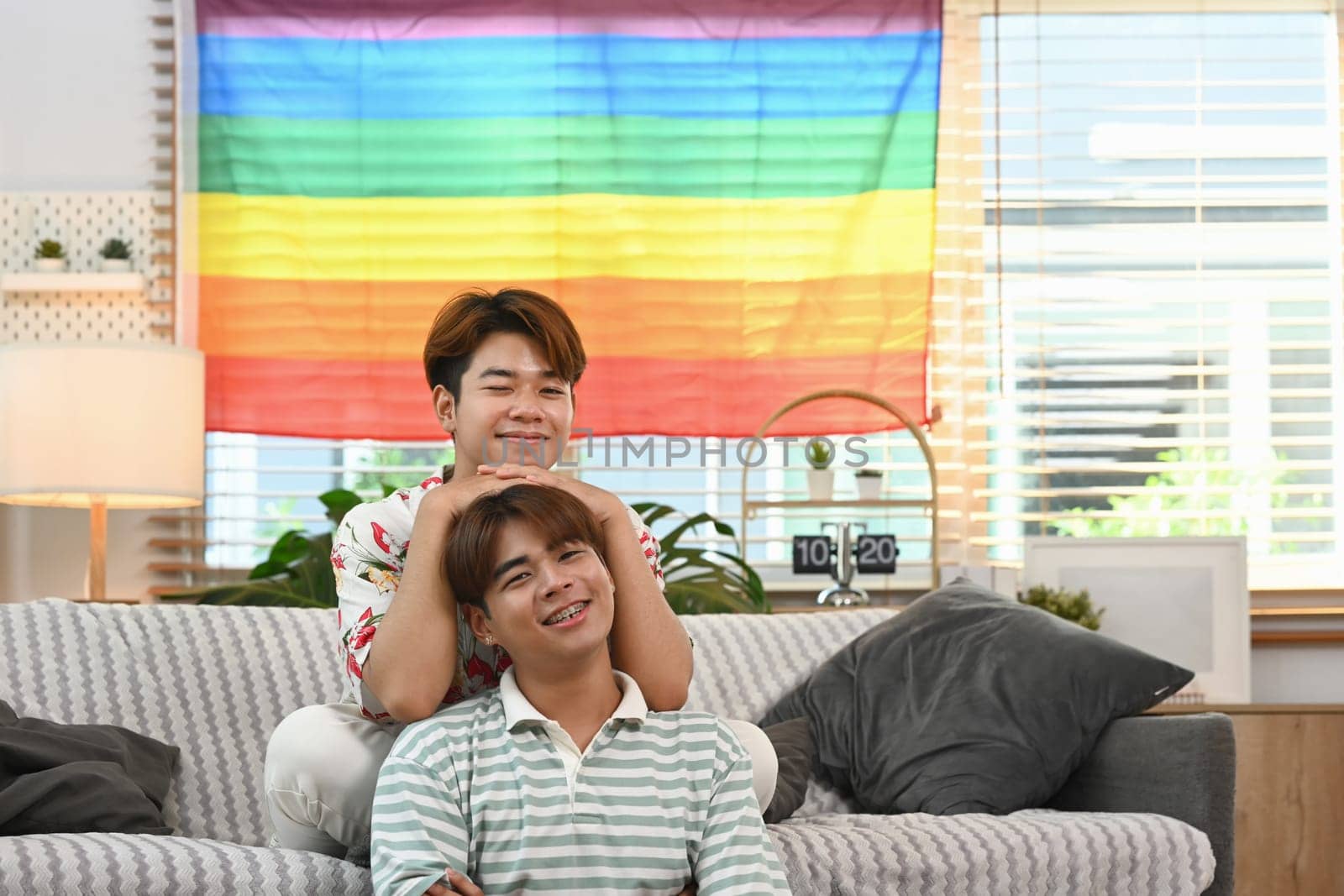 Romantic young gay couple resting together on the sofa at home. LGBTQ people lifestyle concept by prathanchorruangsak