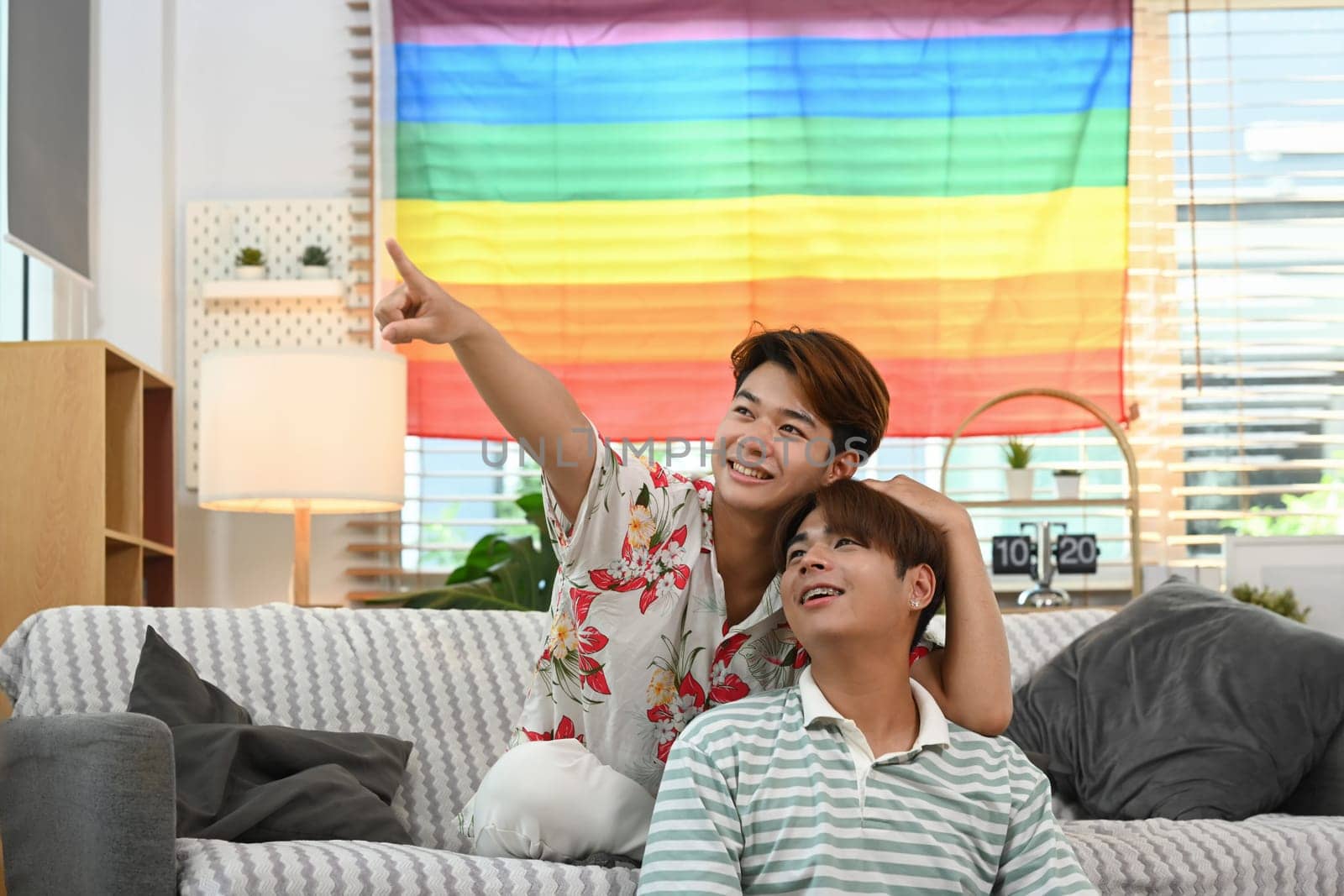 Romantic happy gay couple relaxing together on the couch. LGBT, love and everyday life at home concept by prathanchorruangsak