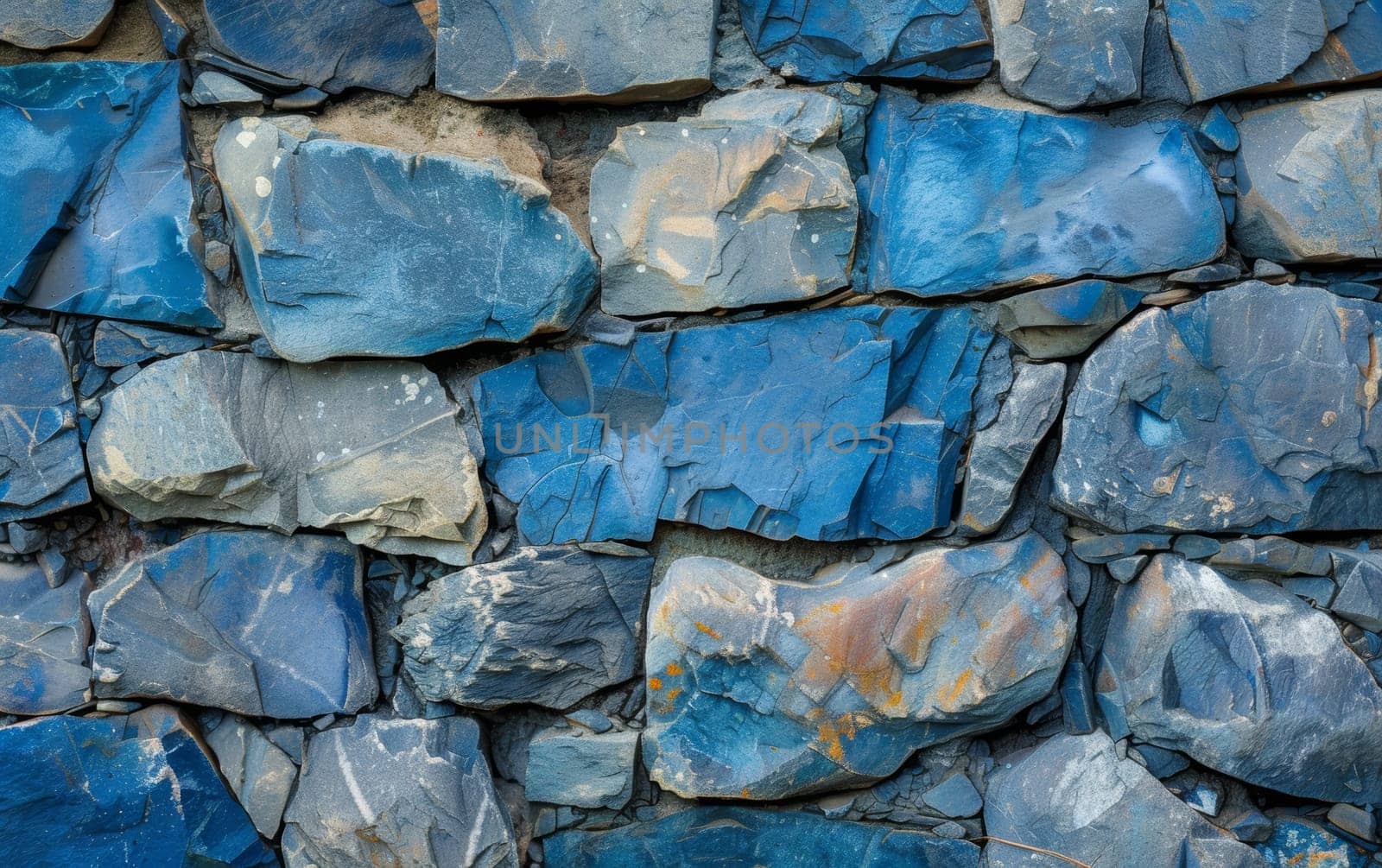Close-up view of a wall made of irregularly shaped stones in various shades of blue