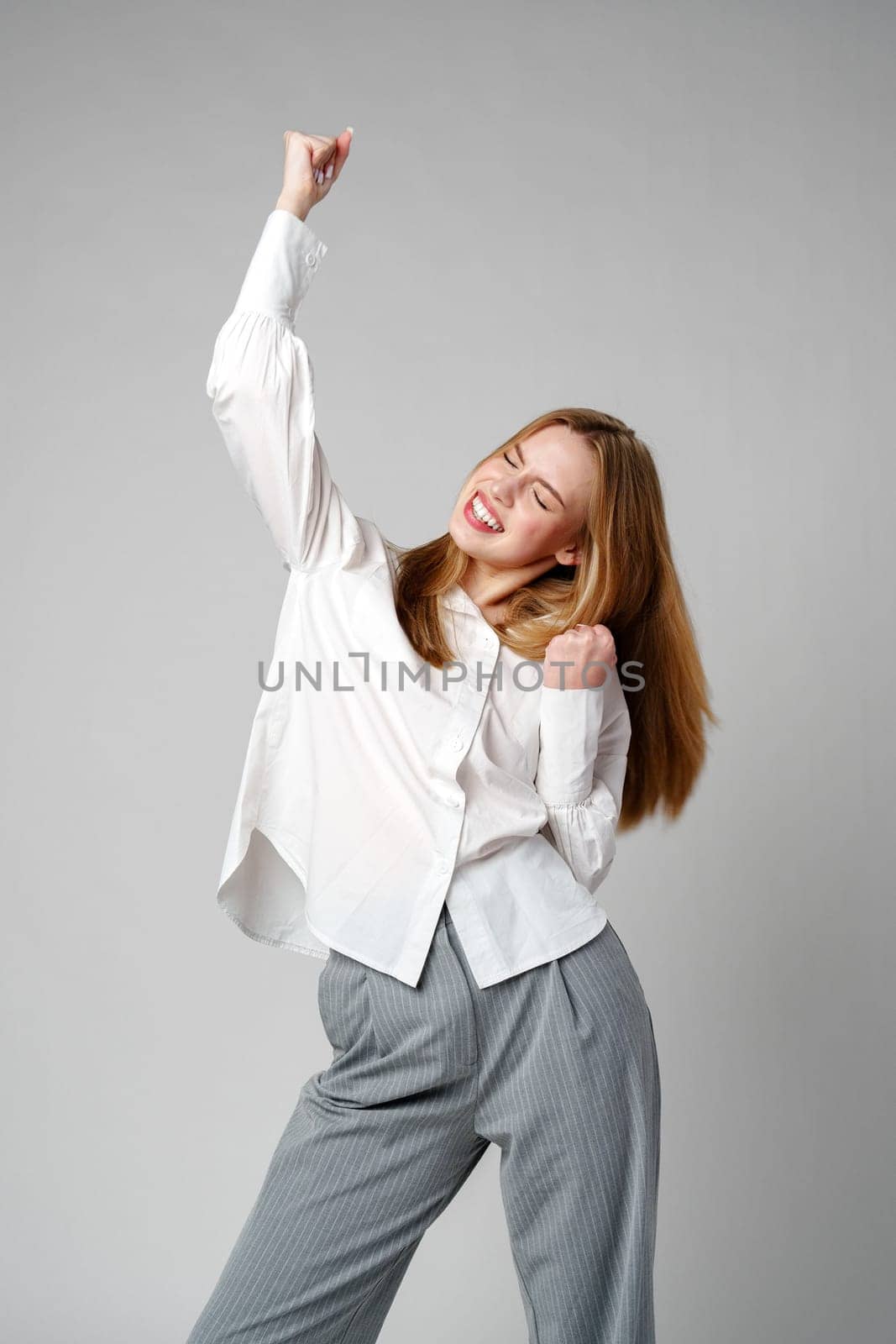 Jubilant Young Woman Celebrating a Victory With a Raised Fist in Studio by Fabrikasimf