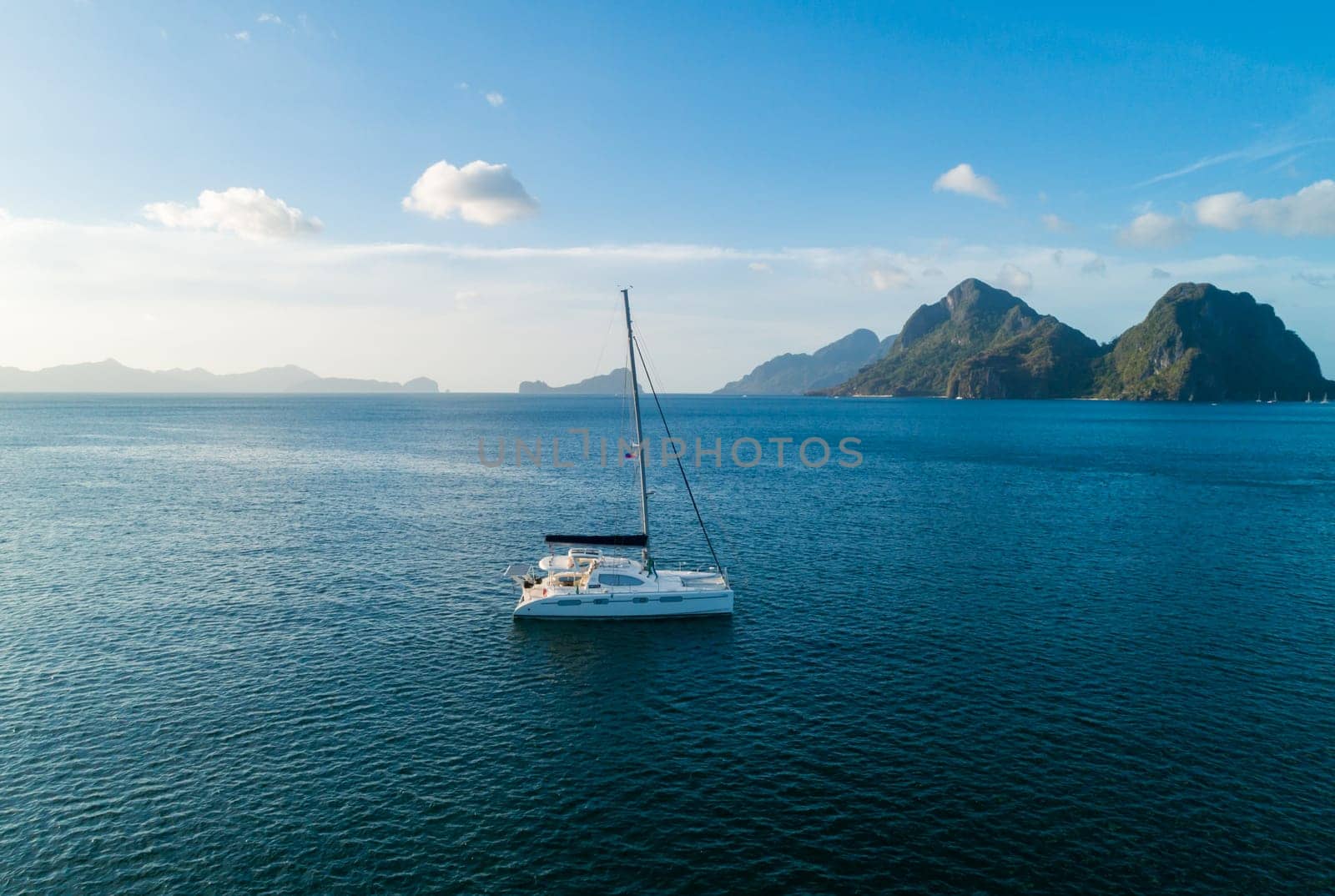 A serene sailboat is anchored in clear, blue tropical waters with picturesque islands in the background.