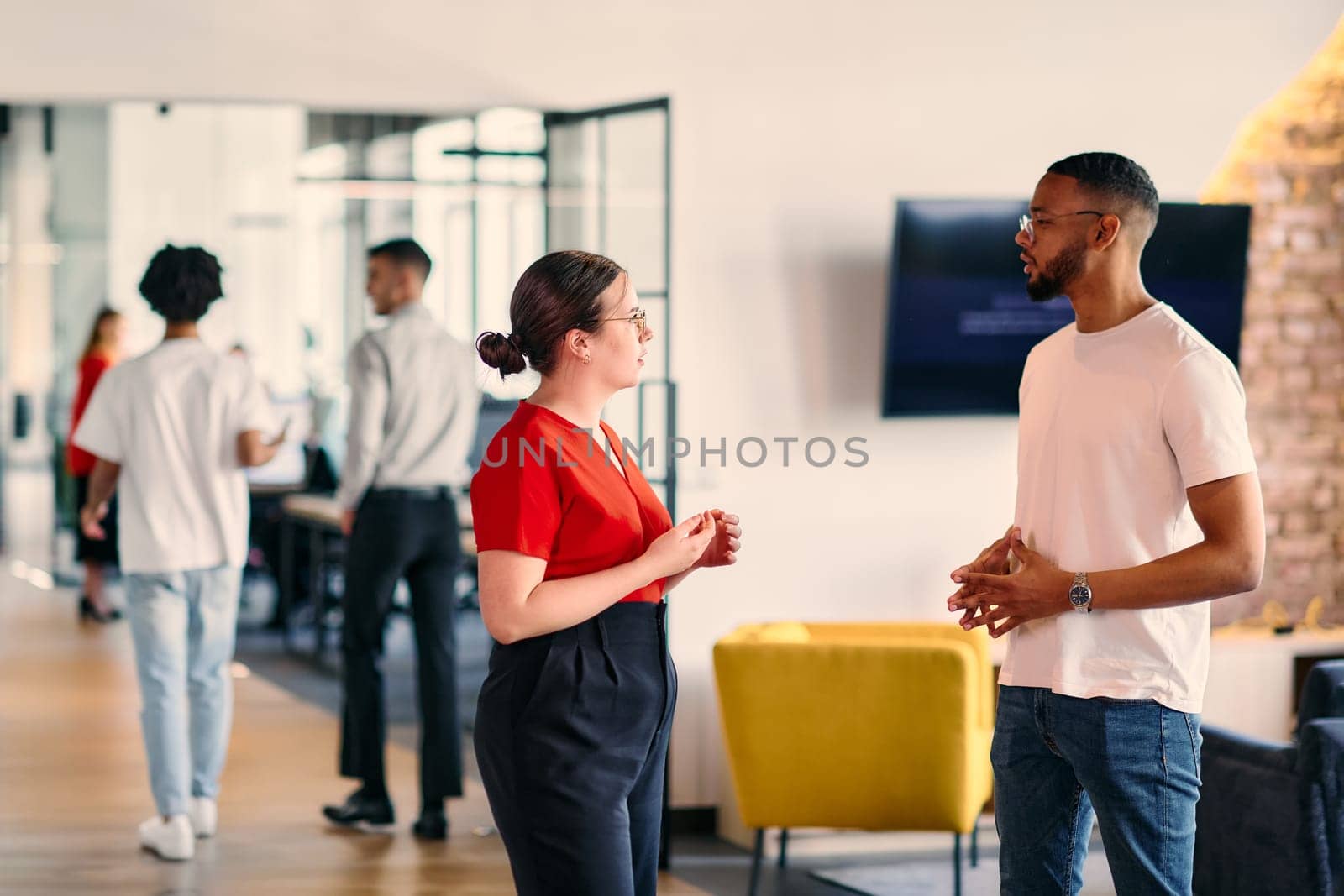 Young business colleagues, including an African American businessman, engage in a conversation about business issues in the hallway of a modern startup coworking center