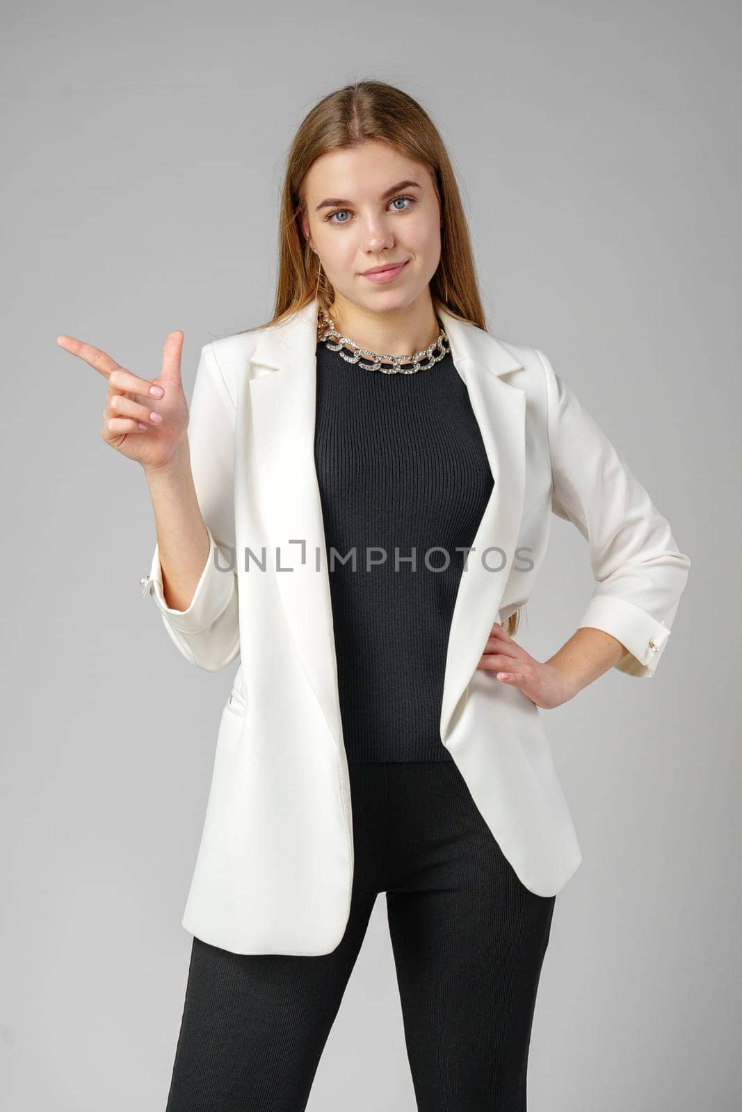 Confident Young Businesswoman Presenting With Hand Gesture in Studio Setting by Fabrikasimf