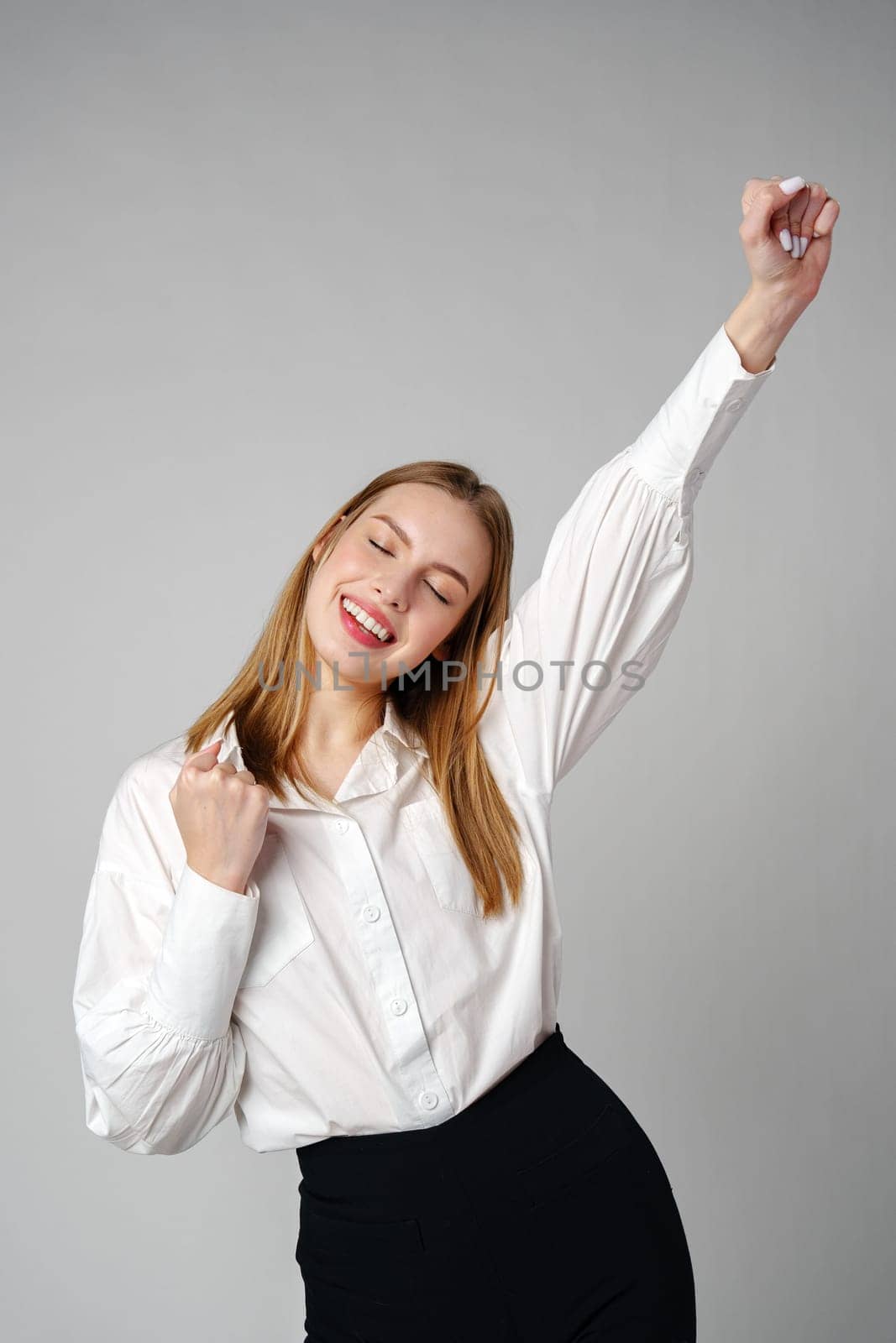 Jubilant Young Woman Celebrating a Victory With a Raised Fist in a Studio