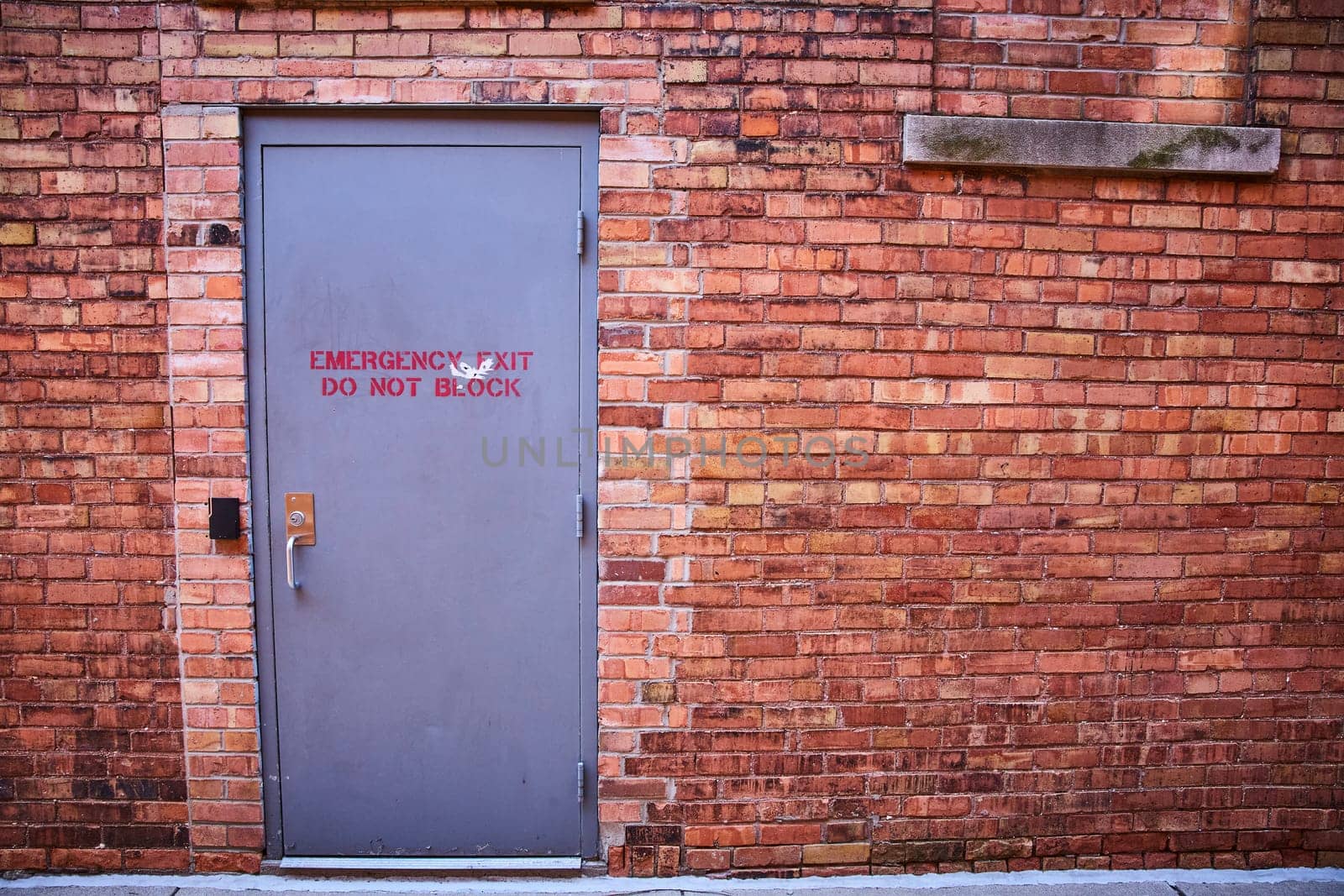 Emergency exit on historic brick wall in downtown Fort Wayne, symbolizing urban safety and security.