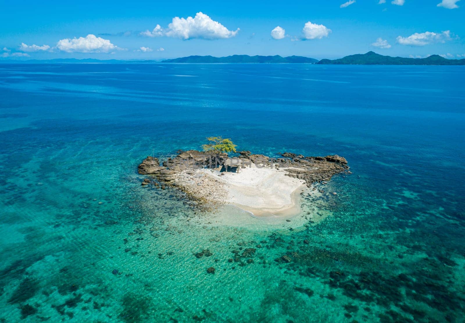 Aerial view of a small tropical island on an atoll with beautiful sandy beach surrounded by coral reef. Tropical island and coral reef. Summer and travel vacation concept by Busker