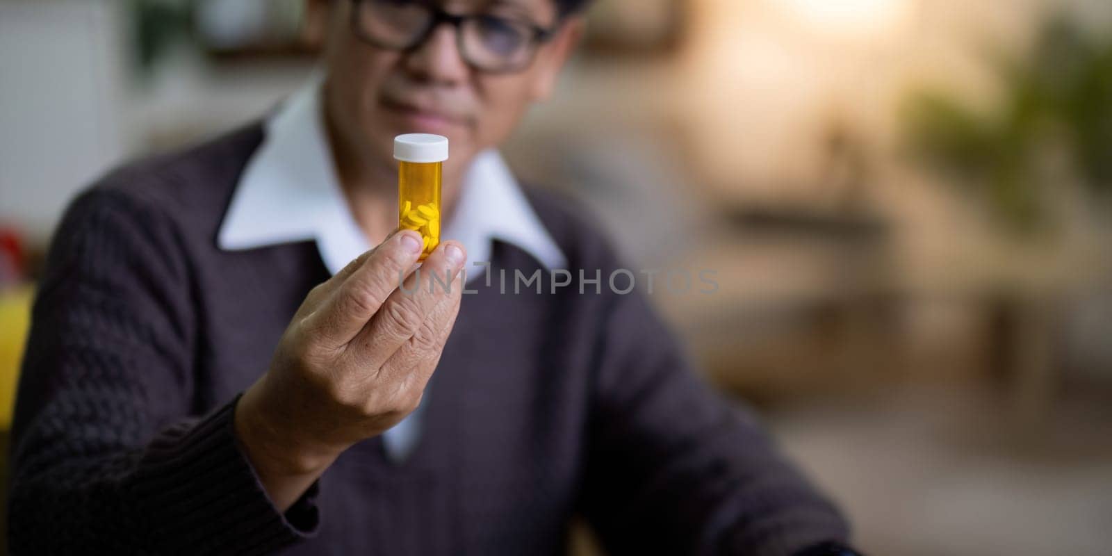Senior asian man examining prescription medication at home by nateemee