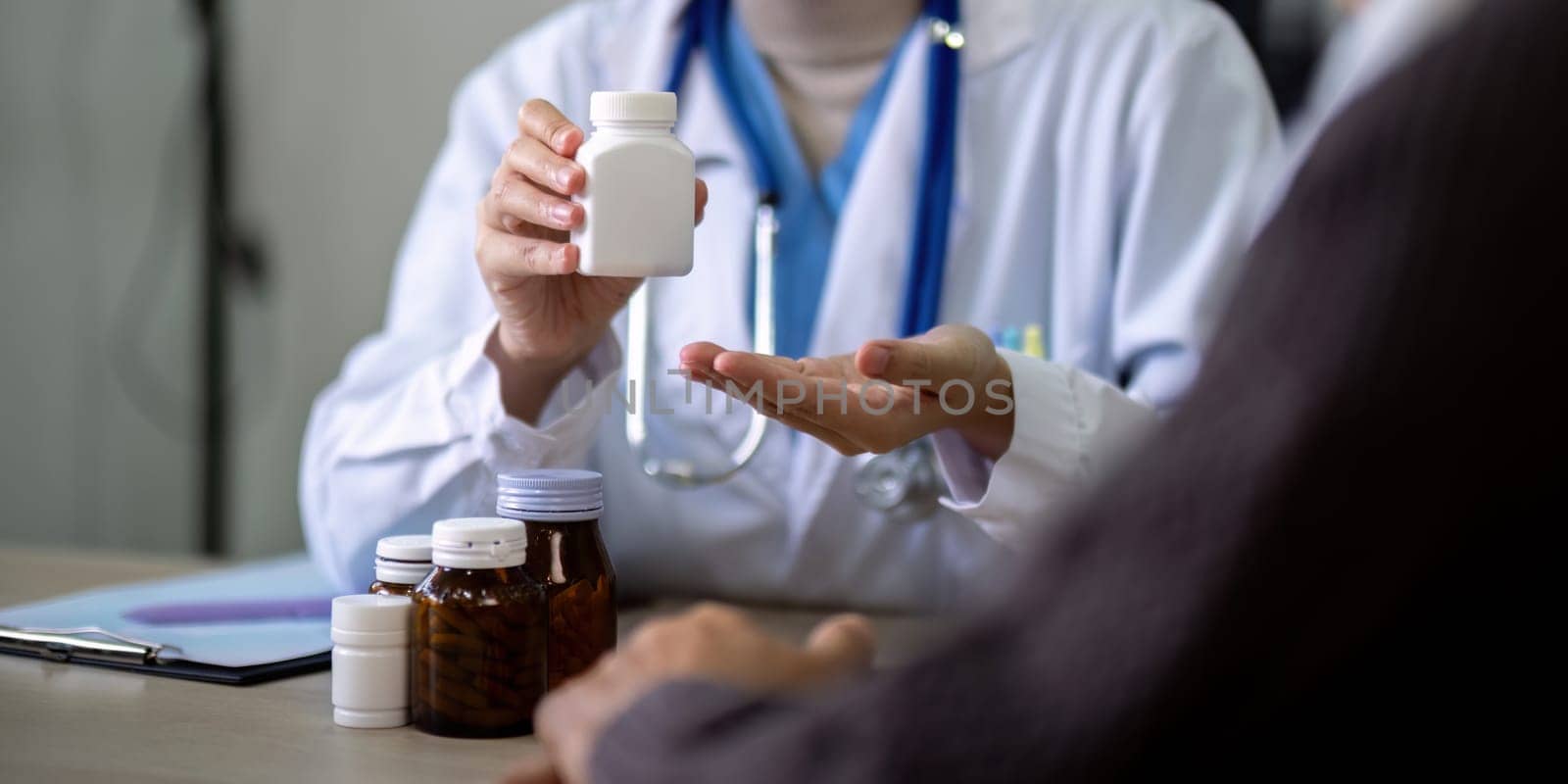 Young woman doctor sit work desk with senior old man patient prescribe drugs or pills, female nurse explain daily dosage of prescribed medicine to elderly man, elderly healthcare concept.