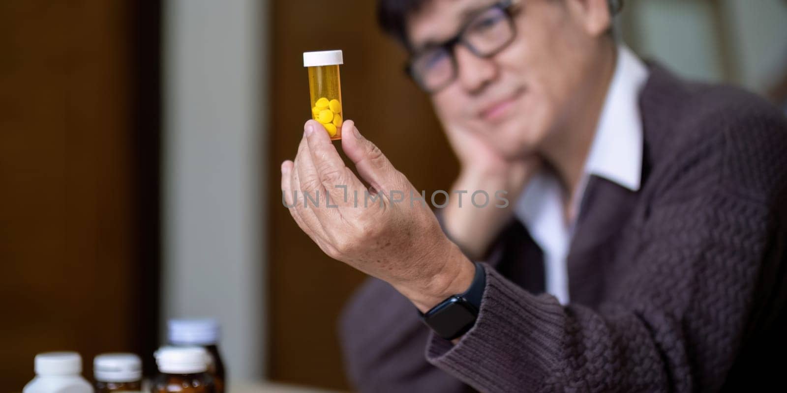 Senior asian man examining prescription medication at home.