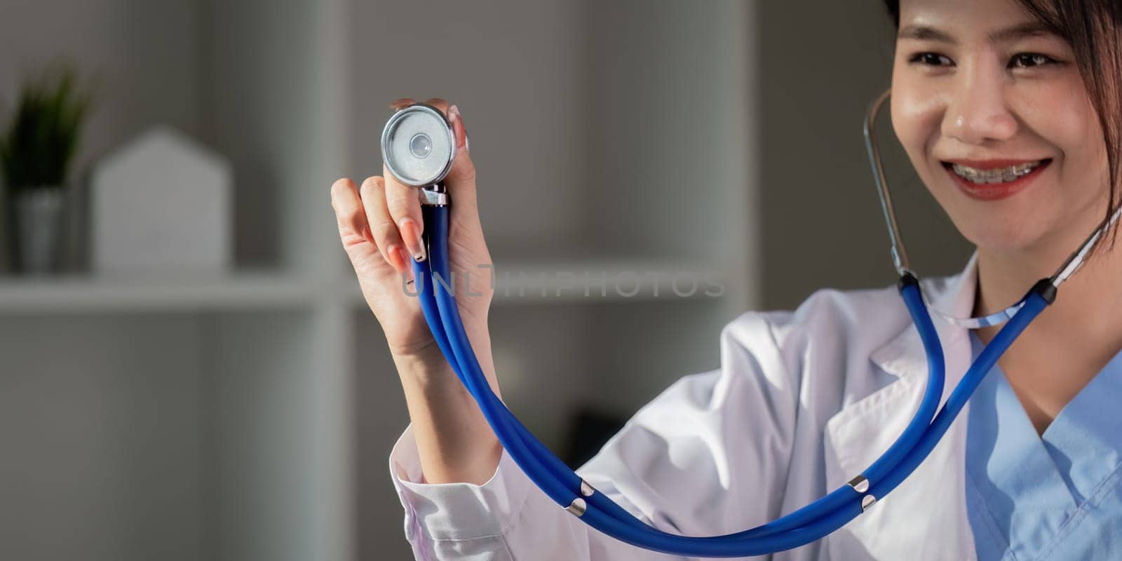 Smiling asian female doctor holding stethoscope, healthcare professional in clinic.