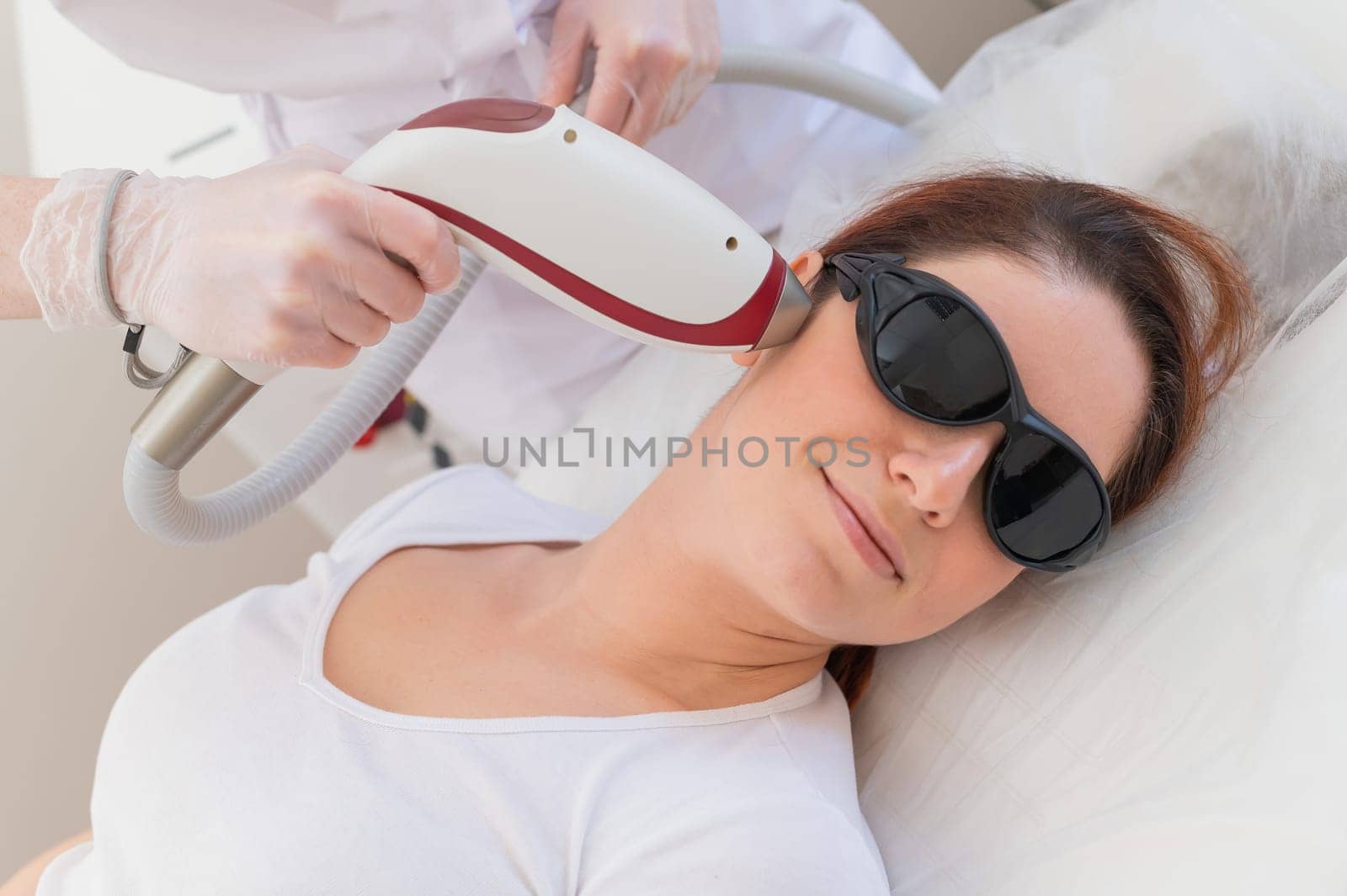 The doctor makes laser hair removal on the face of a woman in the salon. An alternative way to permanently remove unwanted hair.