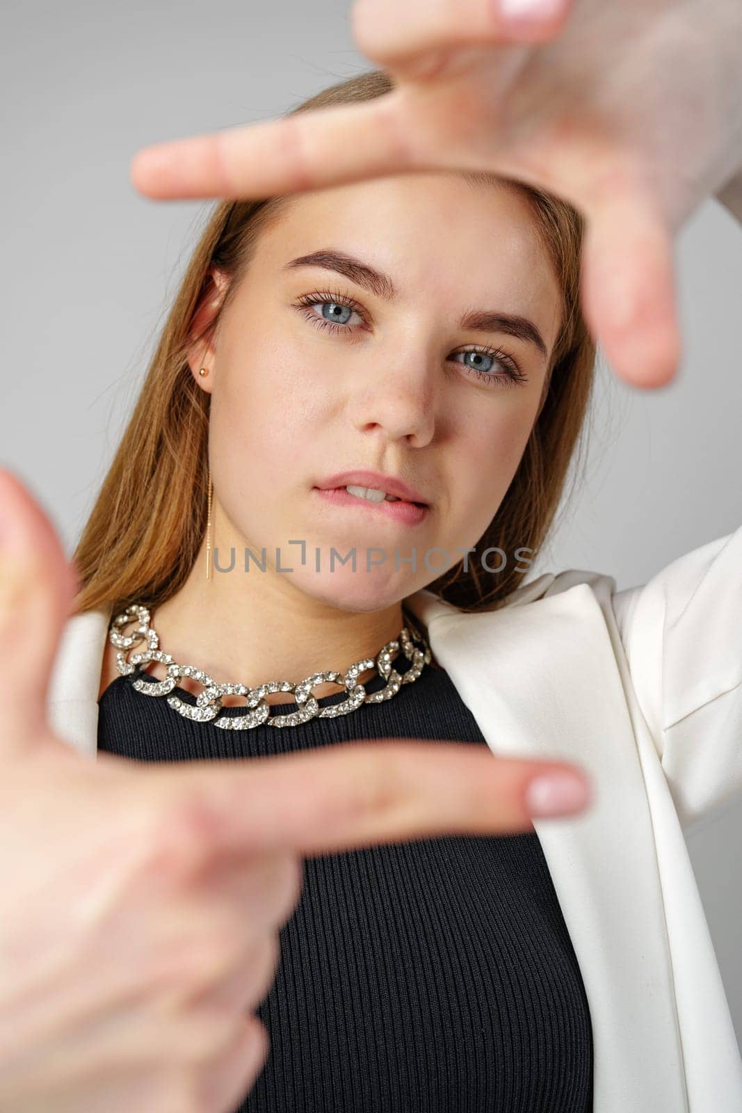 Young Woman Making Frame Gesture With Hands Against a Neutral Background in studio