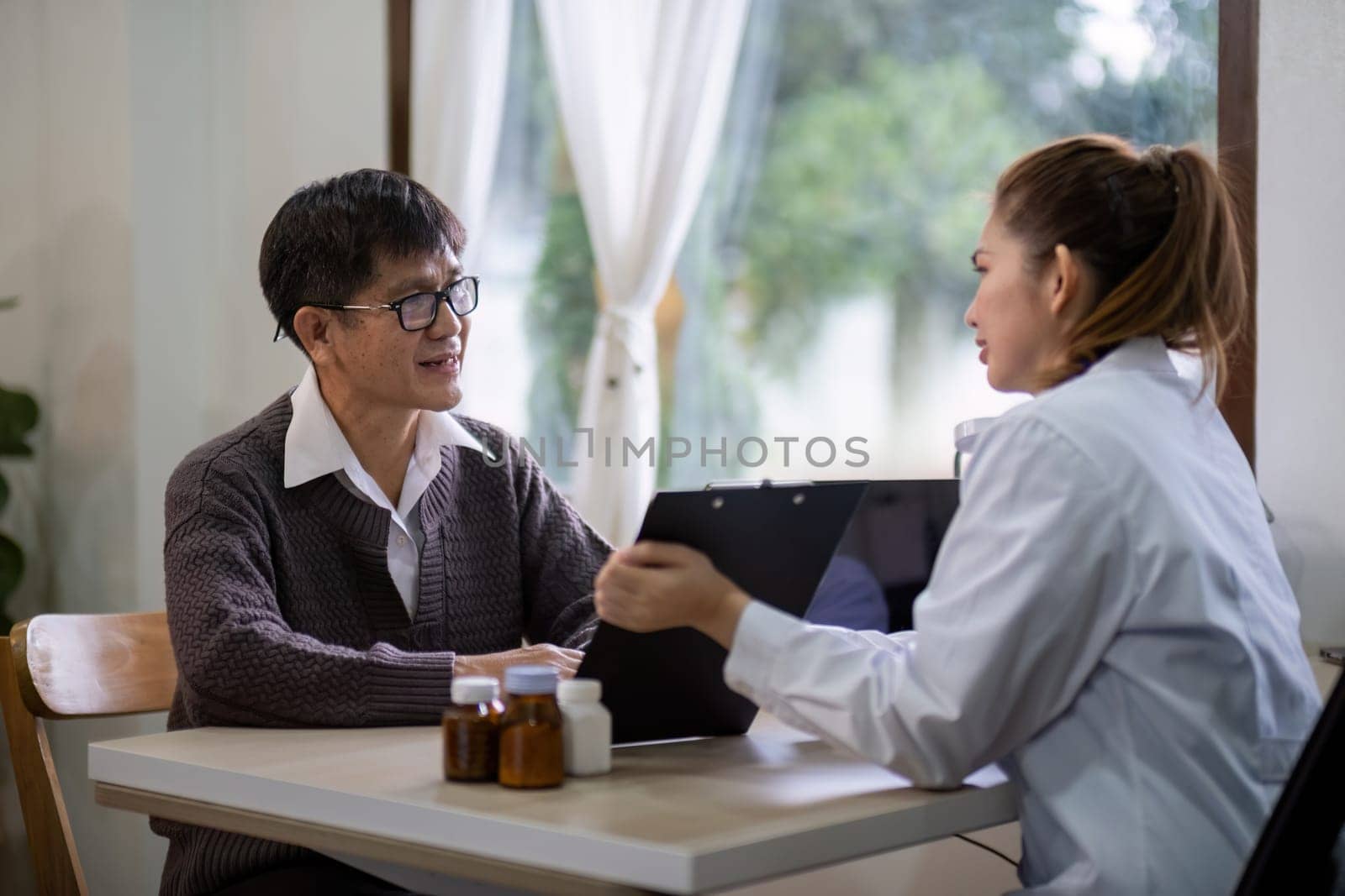 Senior east asian man discussing health with female doctor indoors by nateemee