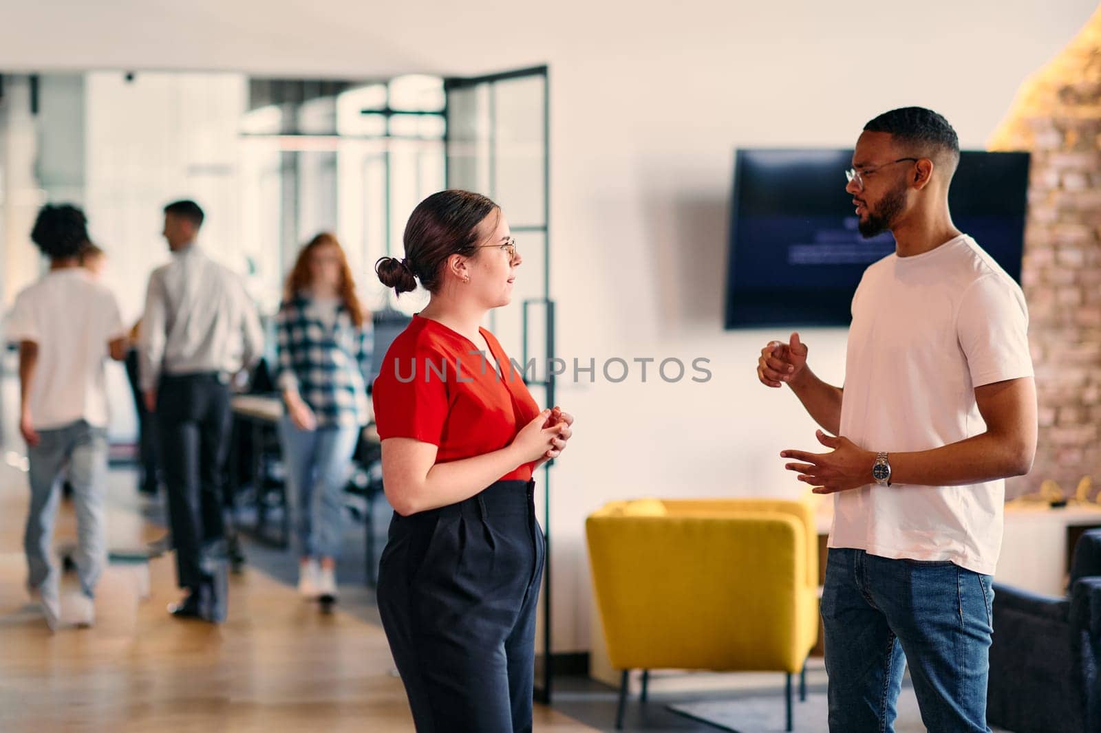 Young business colleagues, including an African American businessman, engage in a conversation about business issues in the hallway of a modern startup coworking center, exemplifying dynamic problem solving and collaboration by dotshock