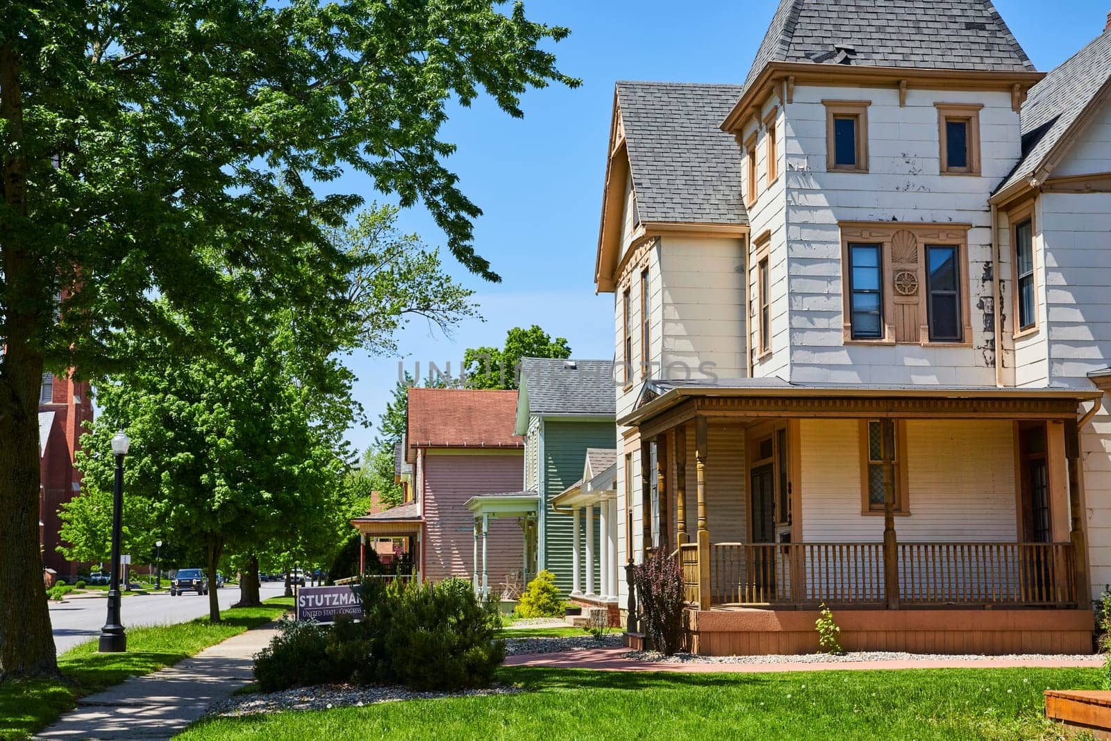 Quaint Victorian homes line a sunny street in historic Fort Wayne, Indiana, embodying serene suburban life.