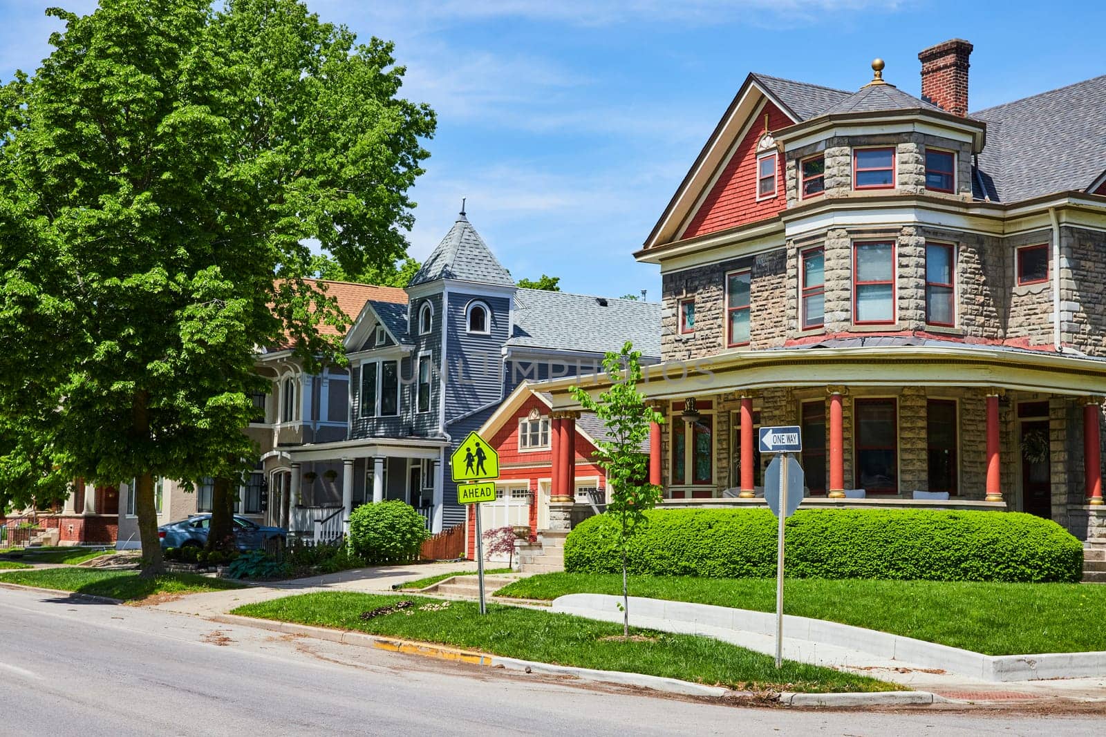 Charming historic homes line a serene street in Fort Wayne, showcasing diverse architectural elegance under clear skies.