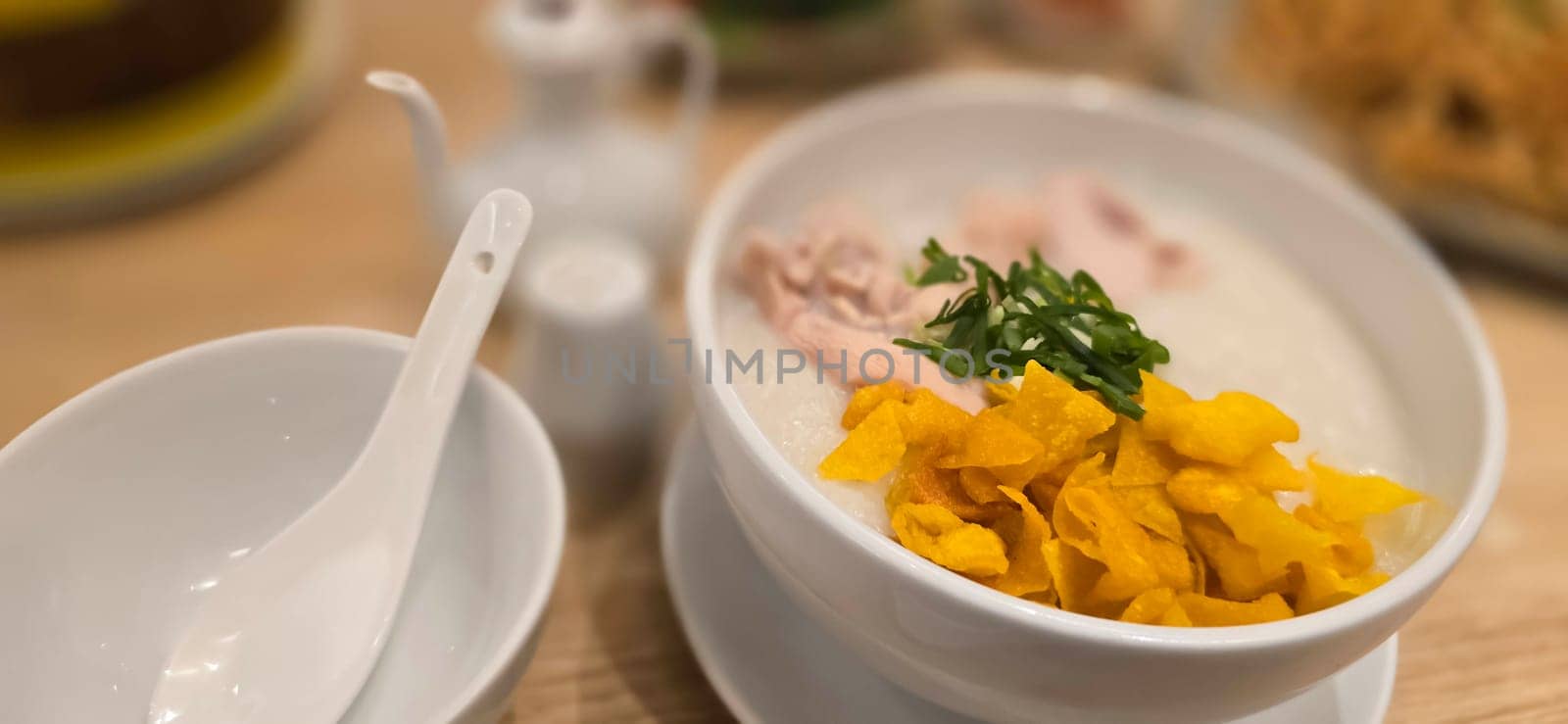 rice porridge with shredded chicken called bubur ayam served with crackers and sliced spring onion and others condiments by antoksena