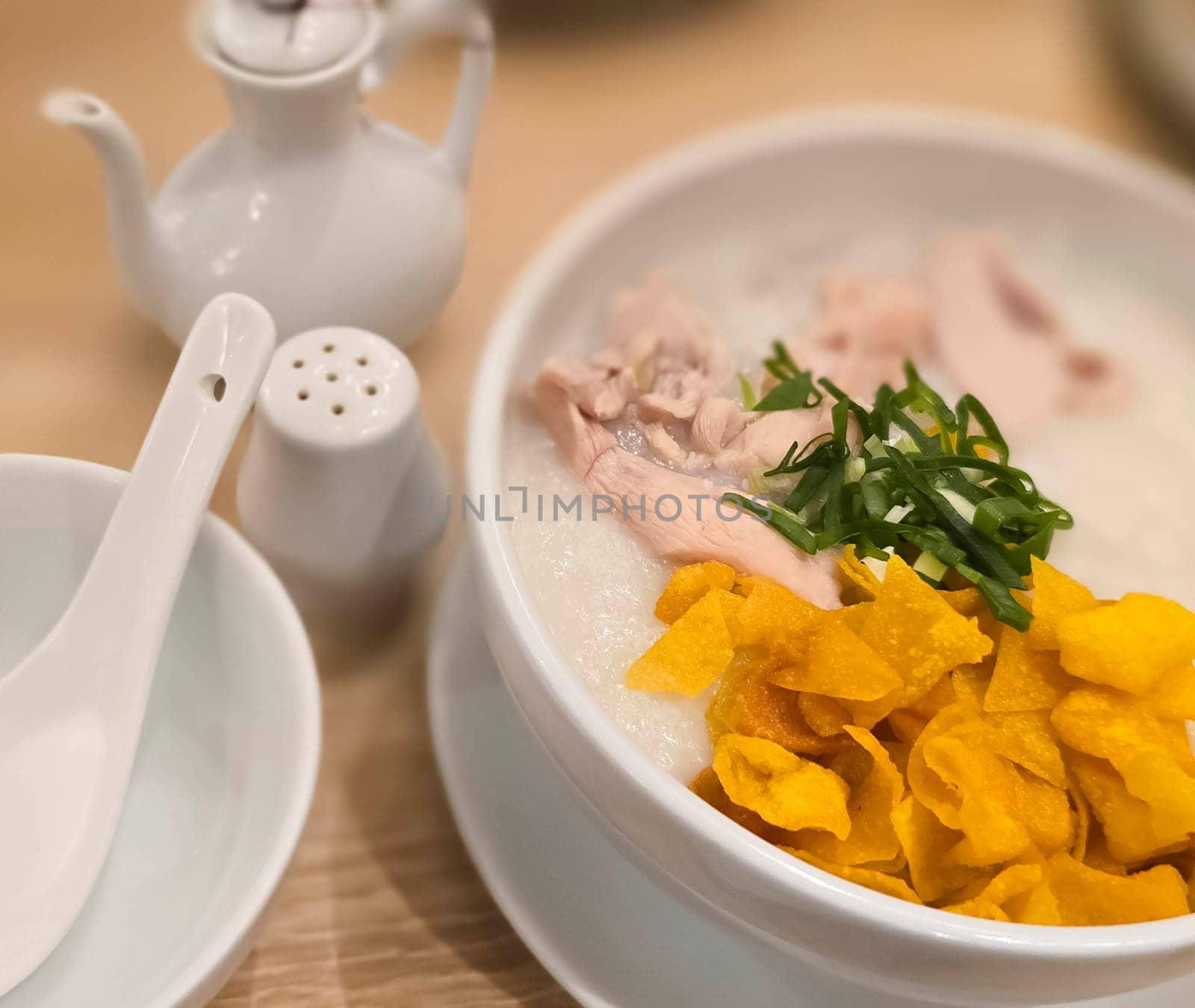rice porridge with shredded chicken called bubur ayam served with crackers and sliced spring onion and others condiments by antoksena