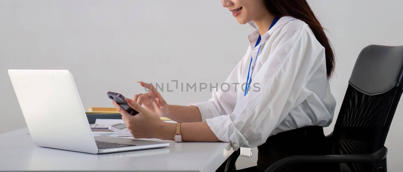 Asian Businesswoman Using Smartphone and Laptop in Office by nateemee