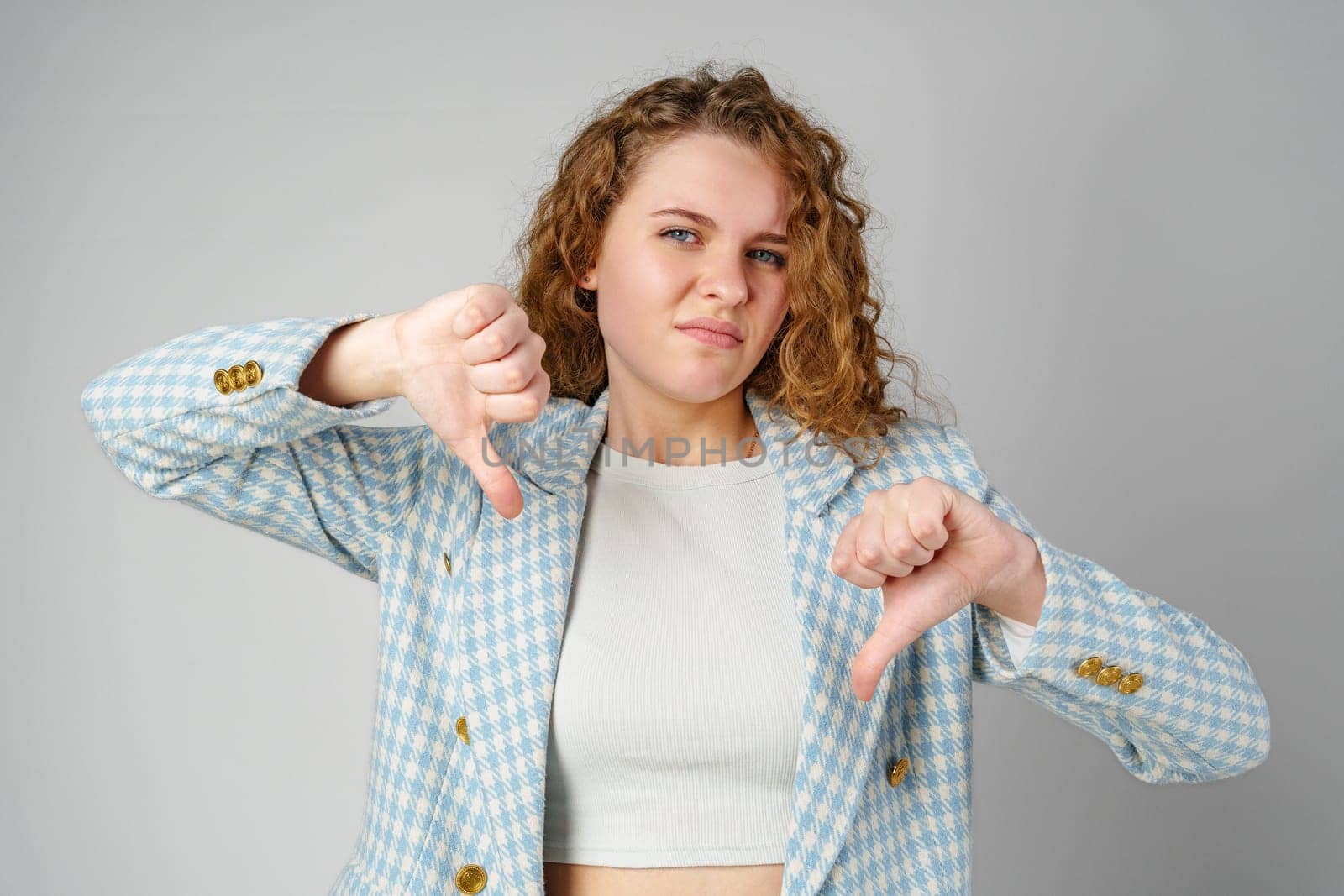 Woman With Curly Hair Giving a Thumbs Down in Studio