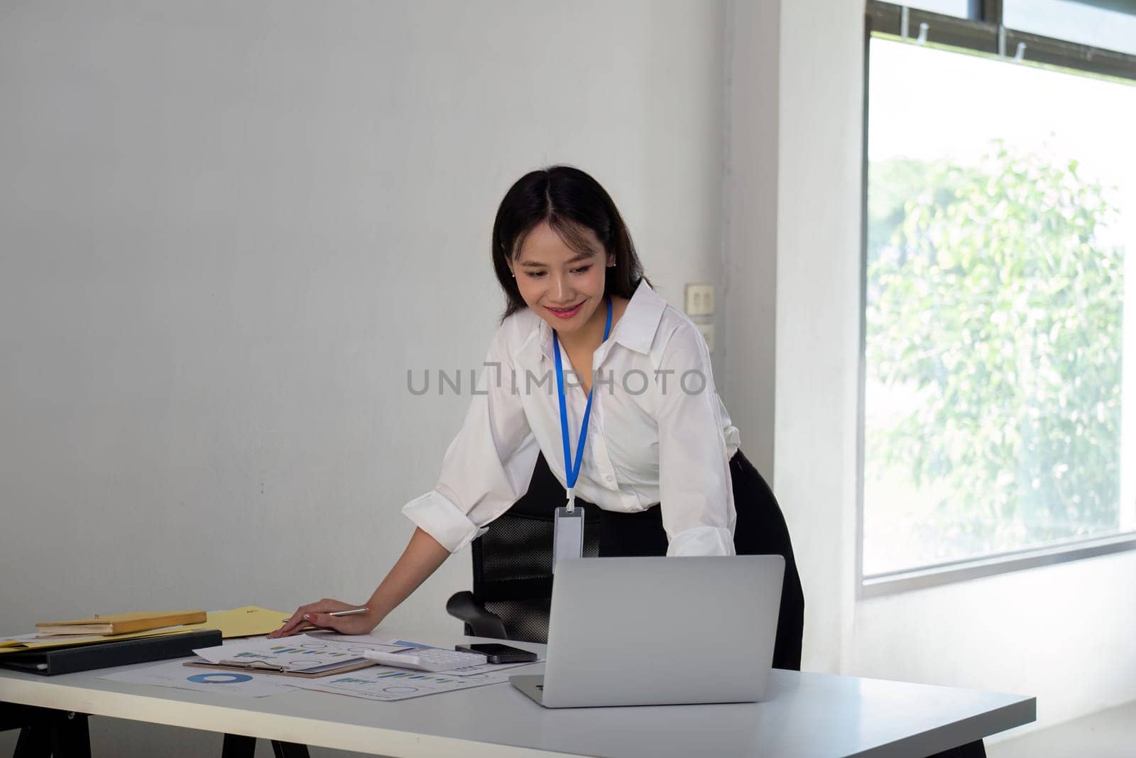 Asian Businesswoman Analyzing Data on Laptop in Modern Office.