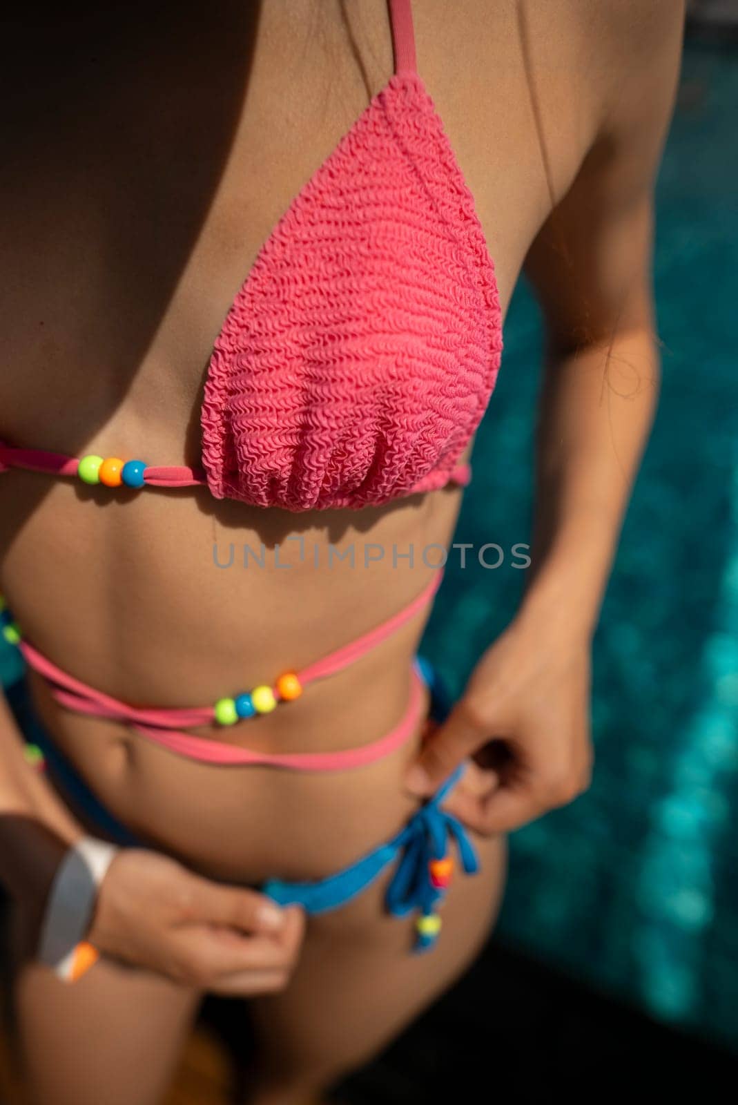 A spirited and sporty lady soaks up the sun's rays in her bikini near the pool. by teksomolika