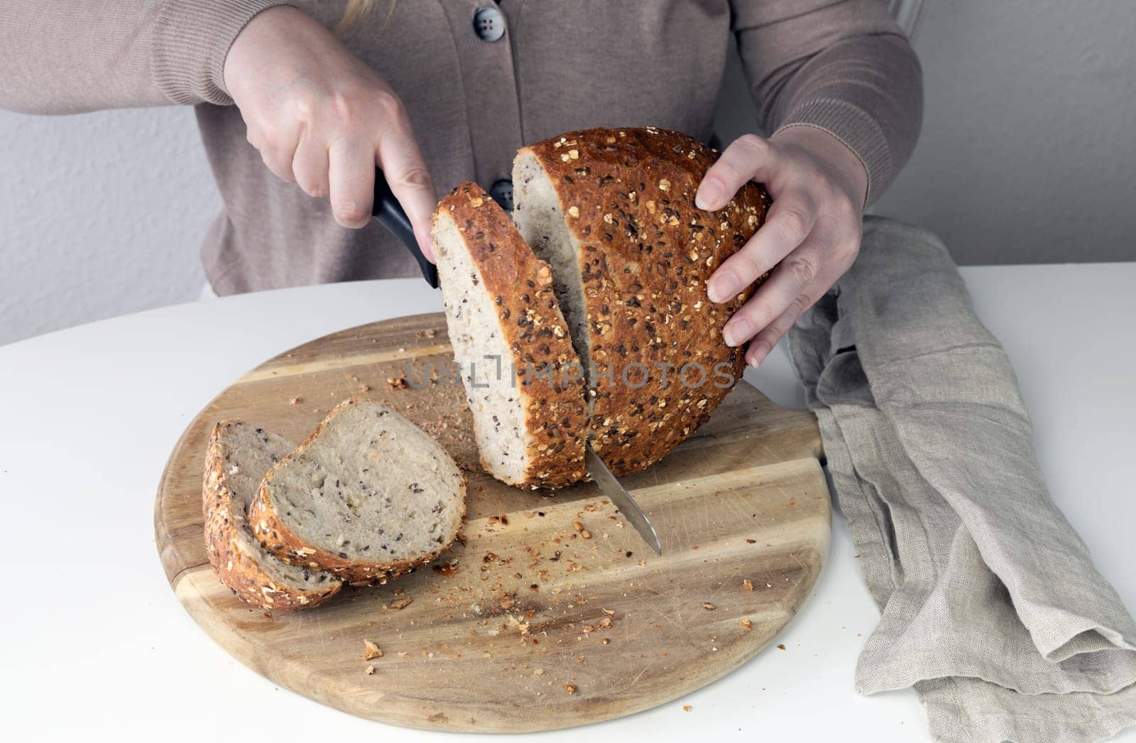 Freshly baked bread on a cutting board. Woman cutting bread.