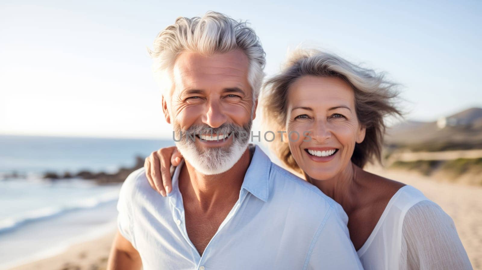 Summer portrait of happy smiling mature gray-haired couple standing together on sunny coast, woman and man enjoying beach vacation at sea