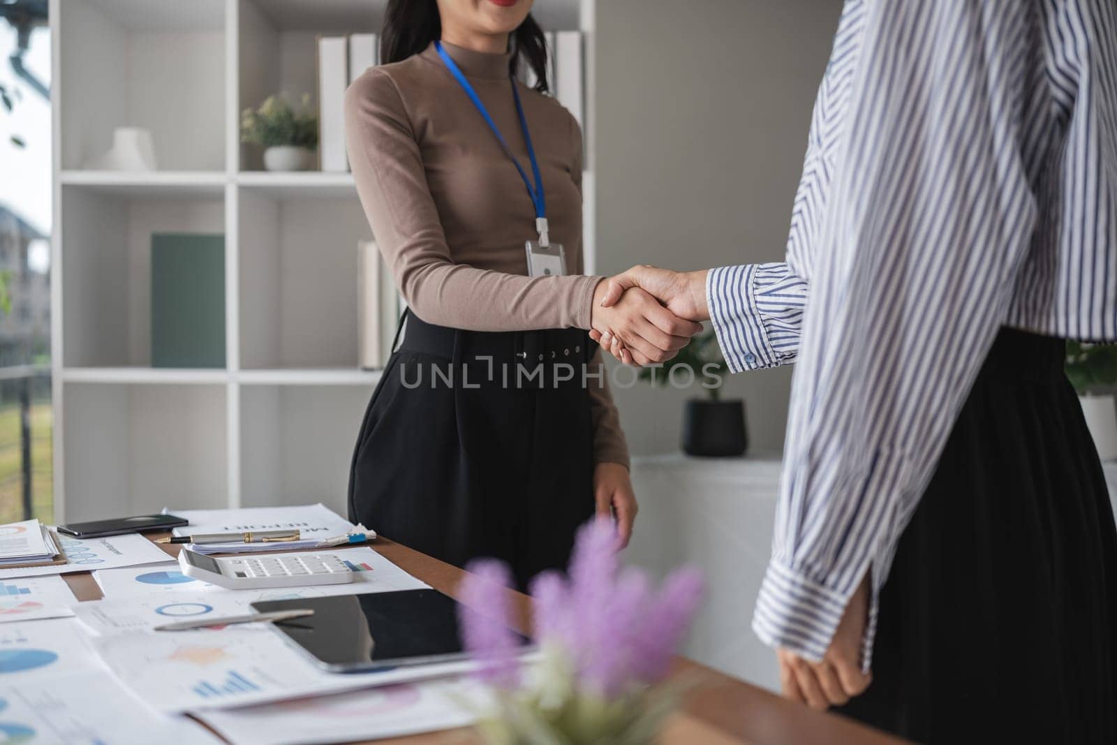 Two Asian businesswomen shaking hands in the office. Concept of partnership and agreement.