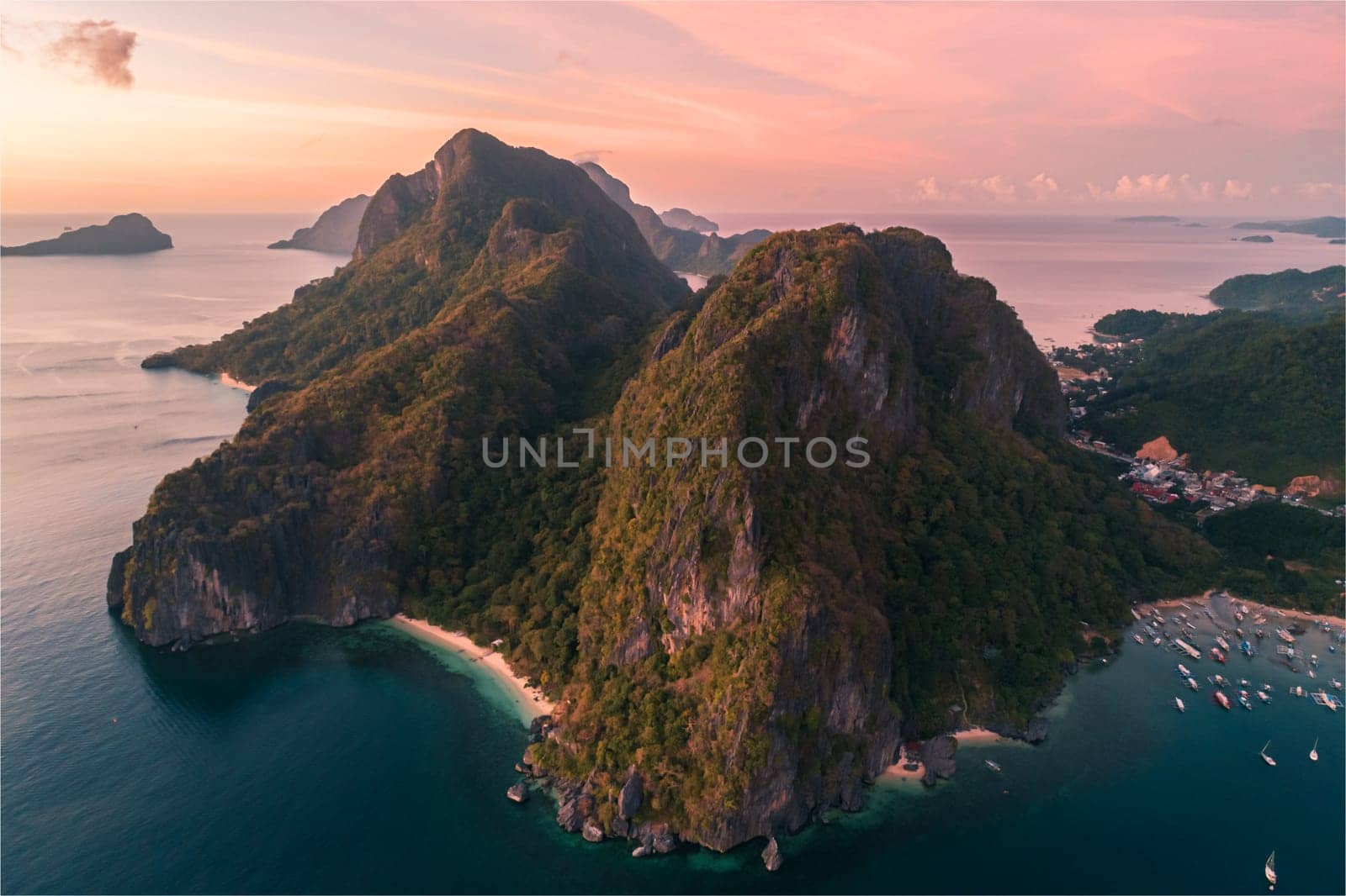 Aerial view of cliffs in the sea, yachts are sailing nearby, mountains covered with tropical forest. El Nido, Palawan, Philippines. by Busker