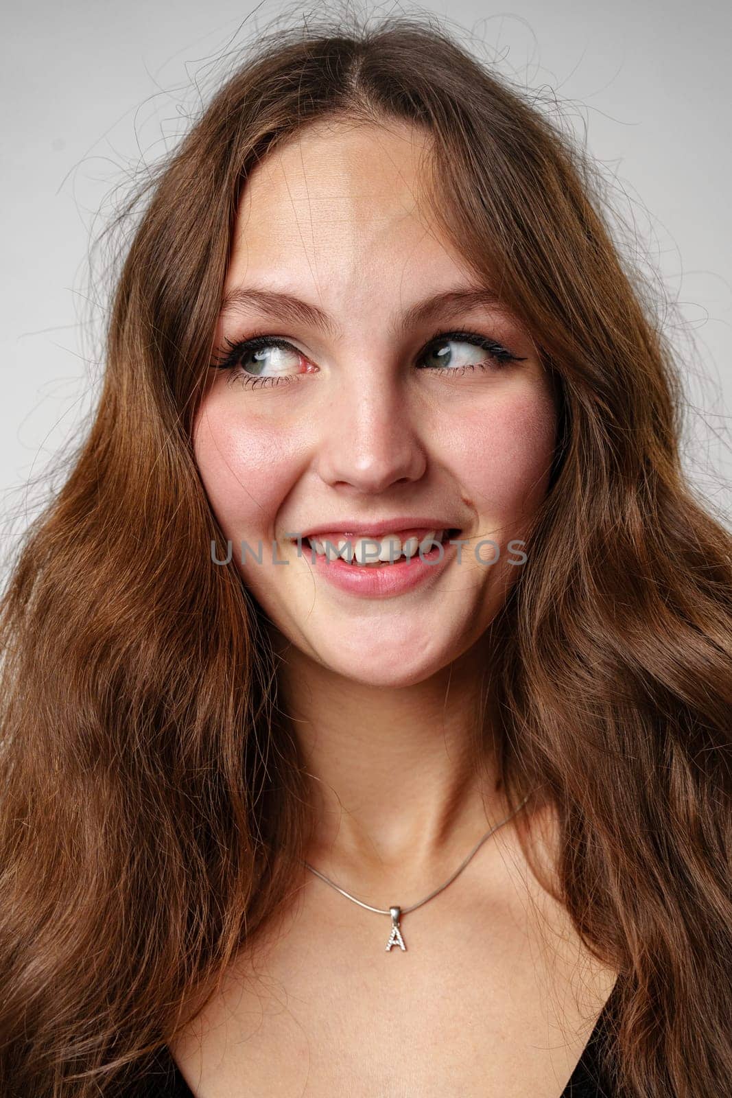 A woman with long brown hair is smiling directly at the camera, showing a sense of joy and positivity. Her facial expression is warm and friendly, radiating happiness and confidence.