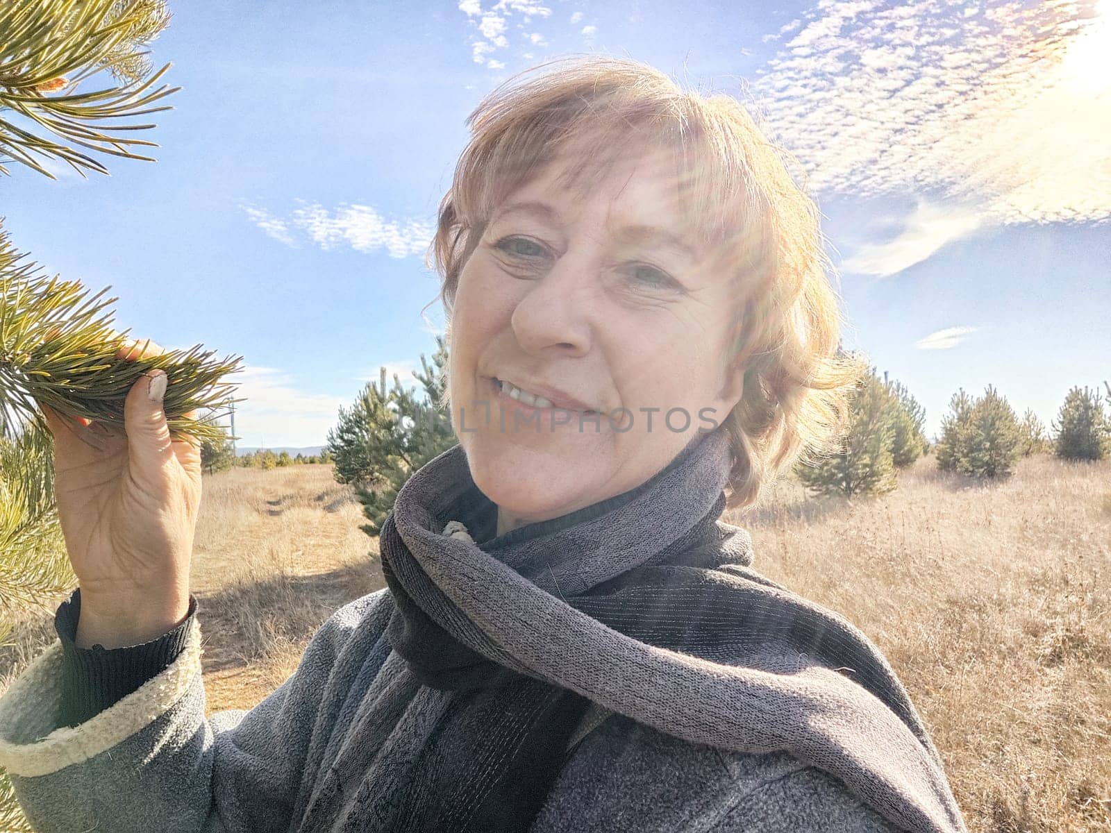 Happy female blonde tourist taking selfie picture outside. Middle aged mature woman having fun on an adventure trip on nature