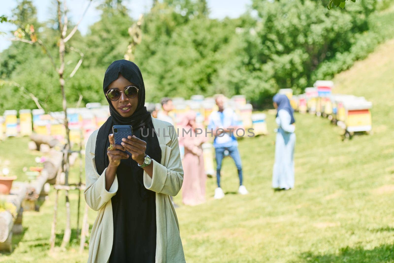 Empowered Middle Eastern Muslim Woman in Hijab Balances Modern Technology and Traditional Beekeeping Business by dotshock
