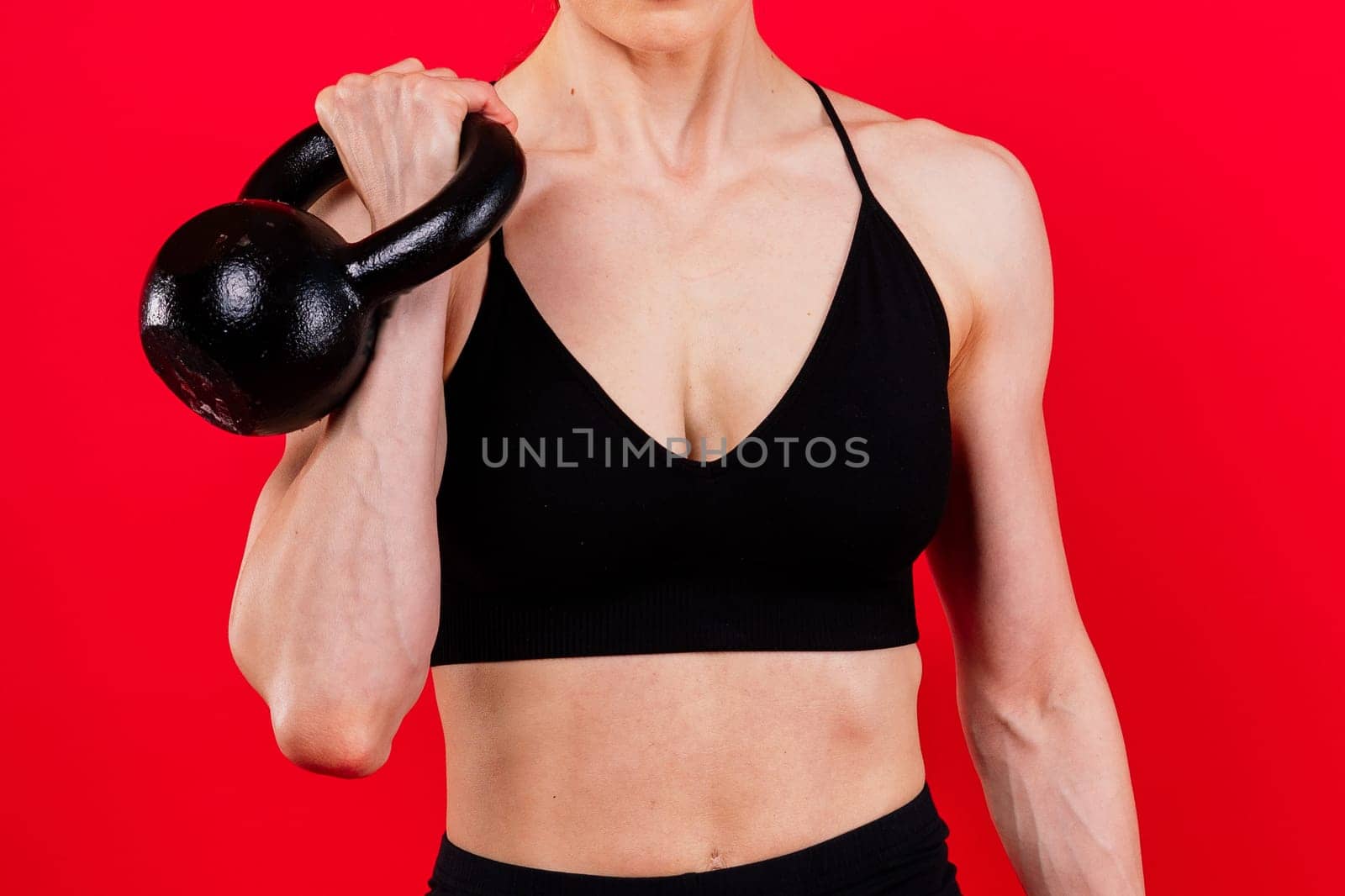 Attractive young athlete with a muscular body exercising crossfit workout with kettlebell.