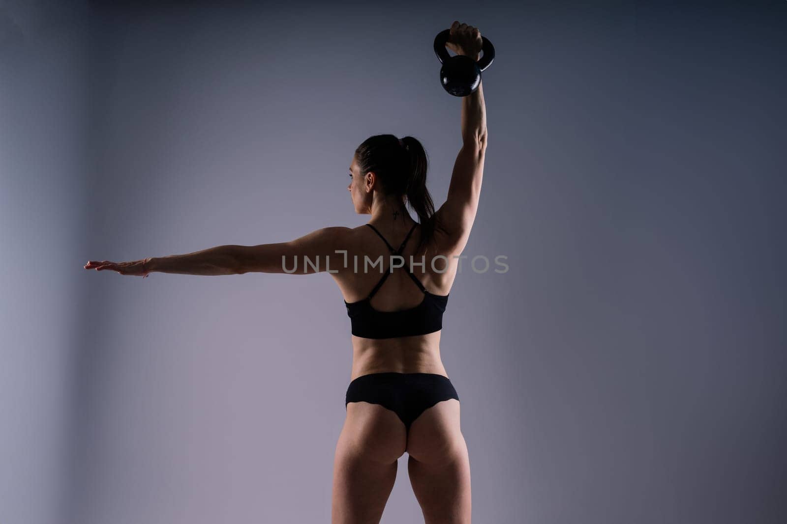 Attractive young athlete with a muscular body exercising crossfit workout with kettlebell.