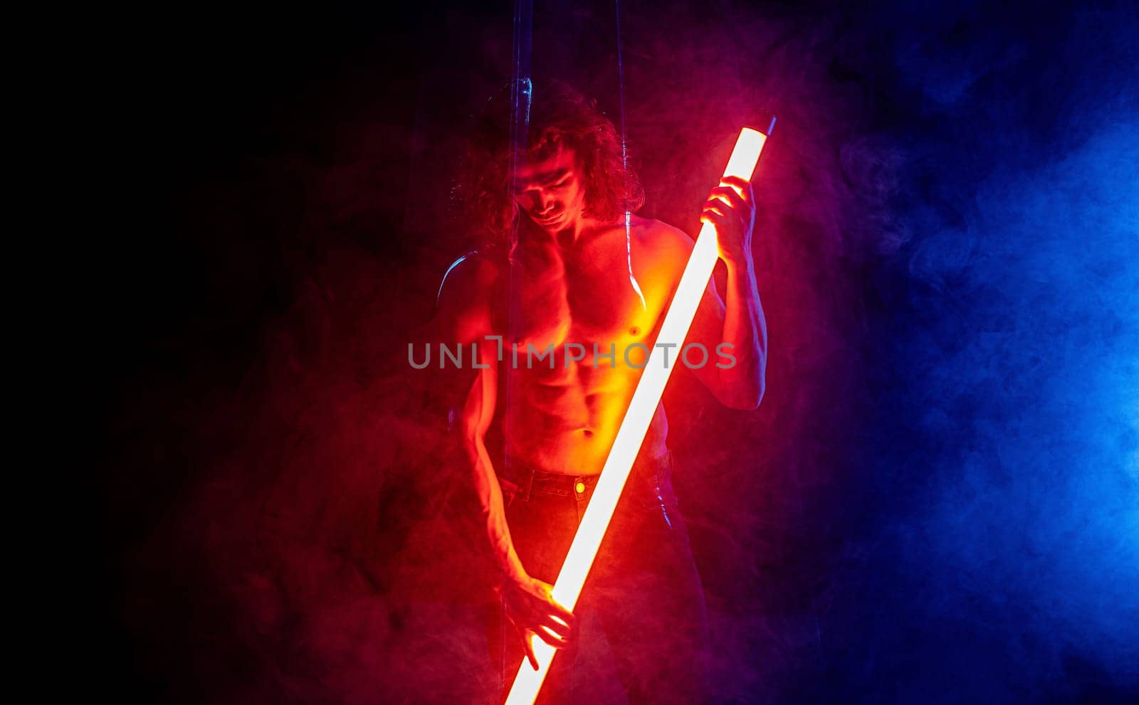 Sporty muscular man with neon light tube,colorful illumination,laser, smoke room by kristina_kokhanova