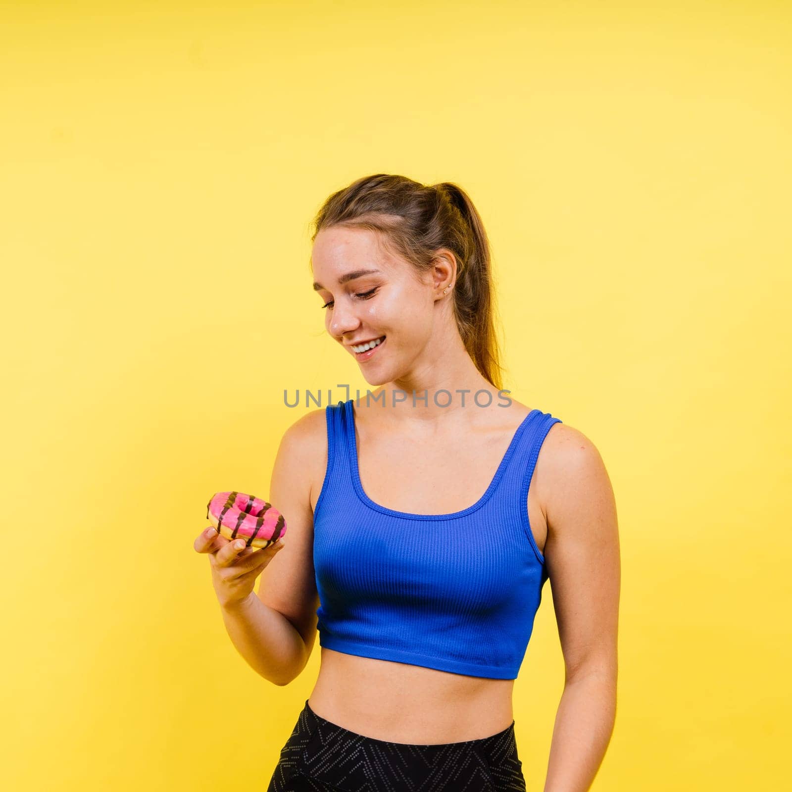 Portrait of beautiful female with chocolate donuts enjoying and looking at the camera