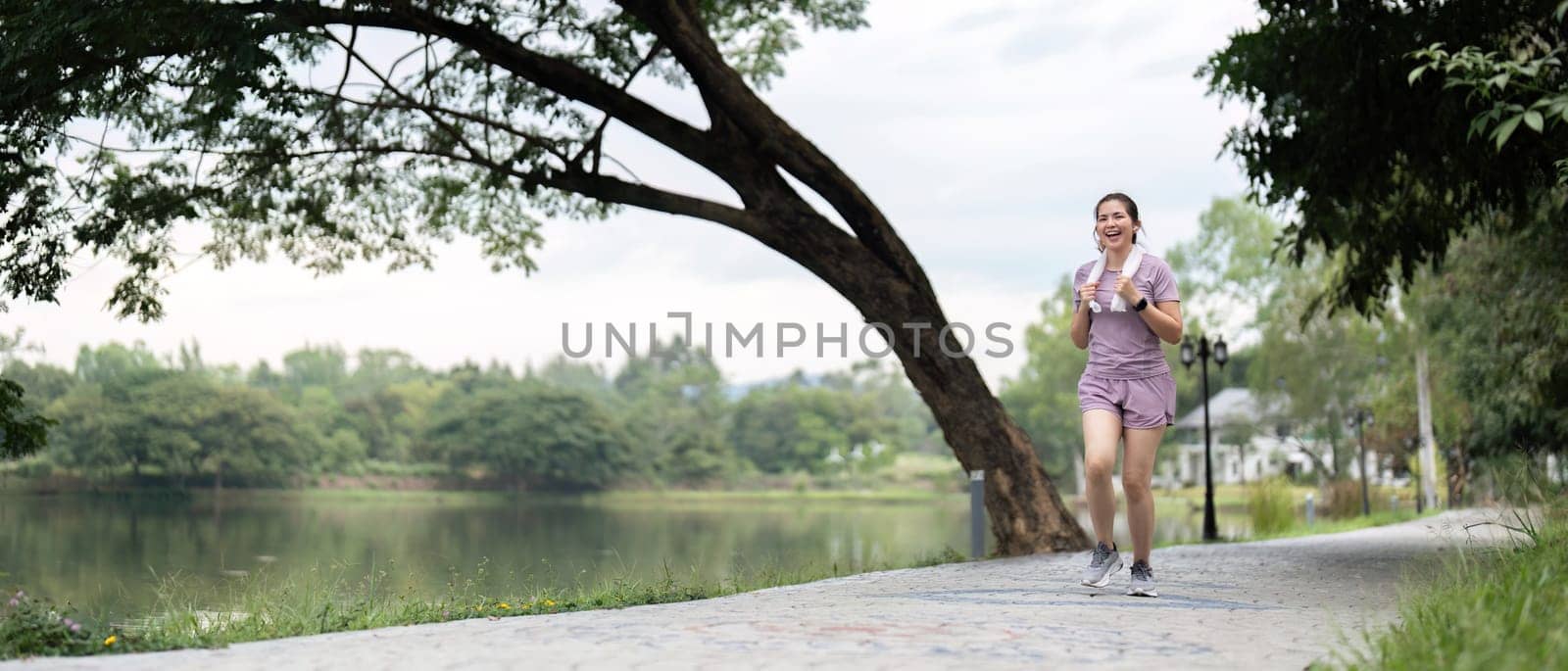 Young asian woman enjoying a morning run in a park. Workout exercise in the morning. Healthy and active lifestyle concept by nateemee
