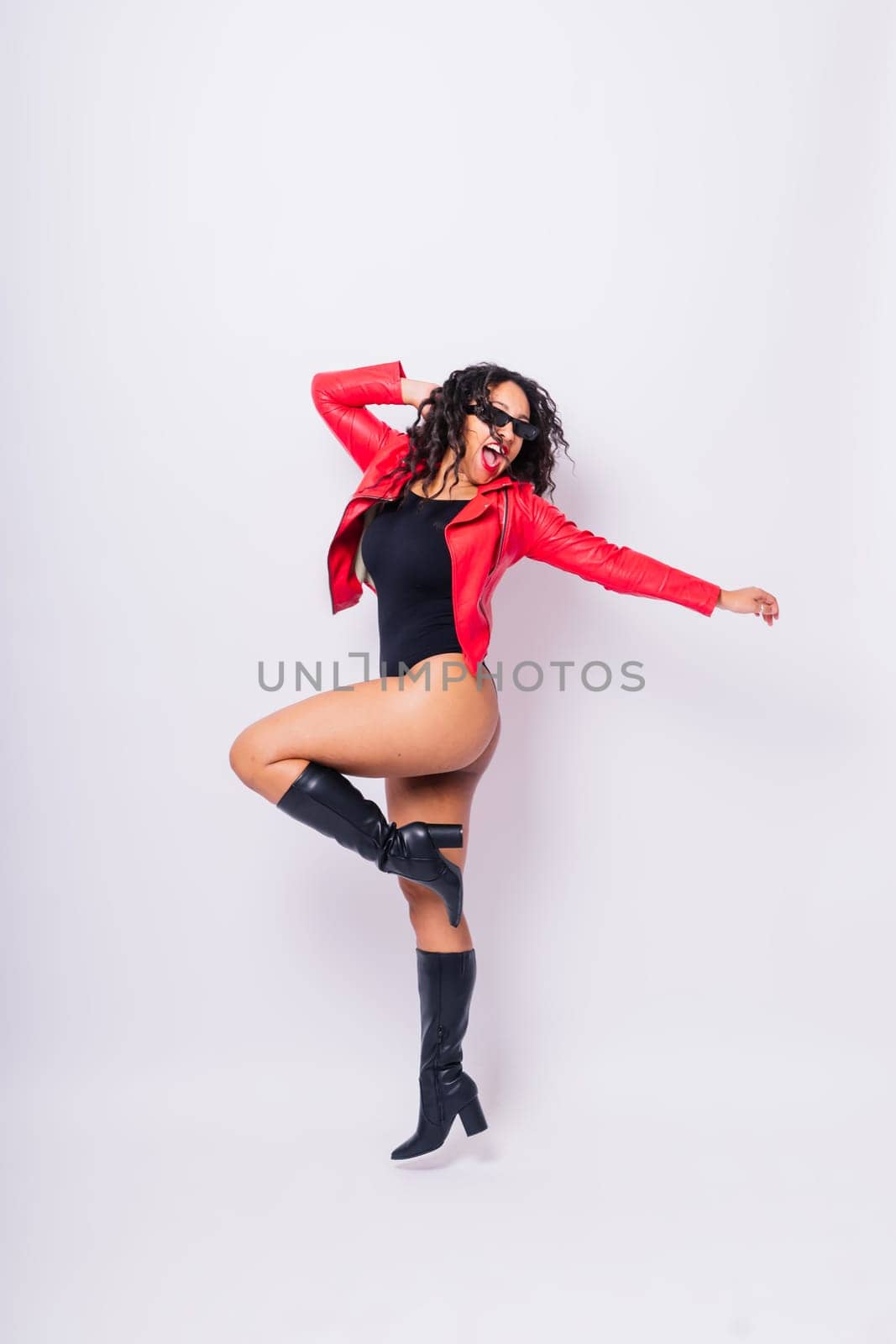 Seductive african woman posing in a black bodysuit and jacket in studio. Fit sporty female.