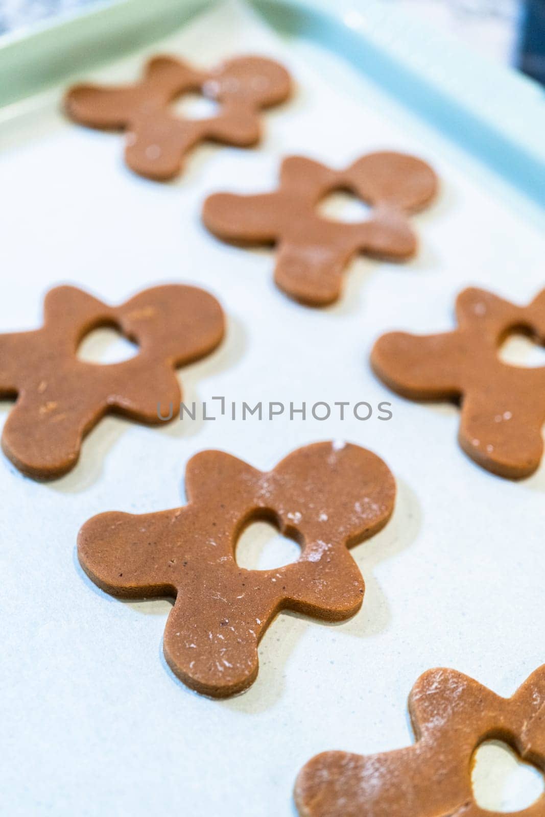 Gingerbread cookies, perfectly chilled and arranged on a baking sheet lined with parchment paper, await their turn to bake in the oven.