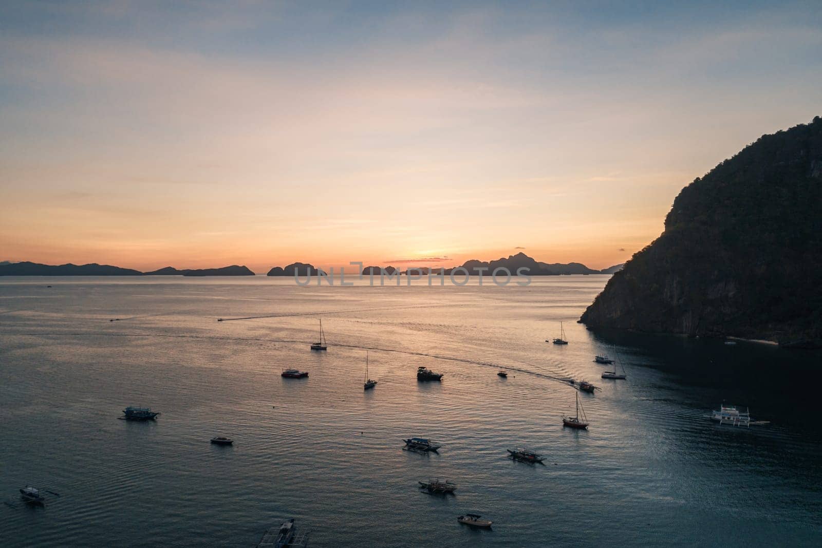 Aerial view of boats and yachts in the tropical bay on the sunset. El Nido, Palawan, Philippines. Travel concept.