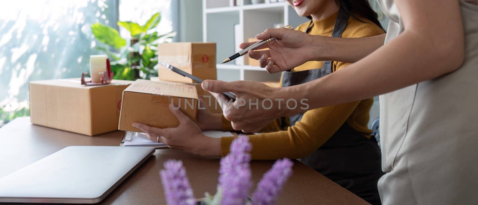 Entrepreneurs preparing packages in a bright home office.