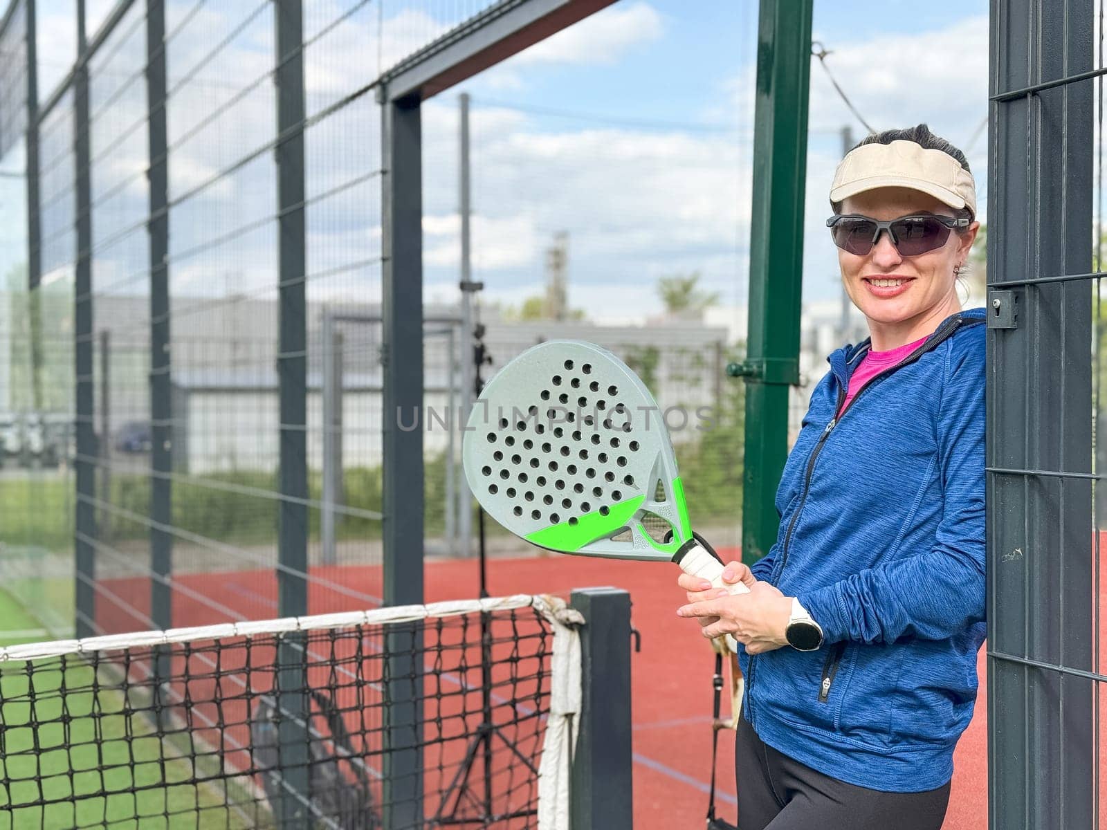 Woman playing padel in a green grass padel court behind the net by Andelov13